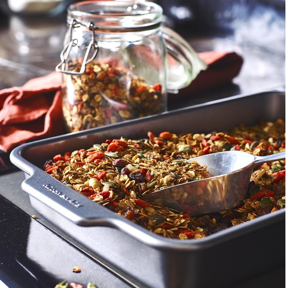Fındık, tohum ve meyveli granola, kepçeli bir fırın tepsisinde.