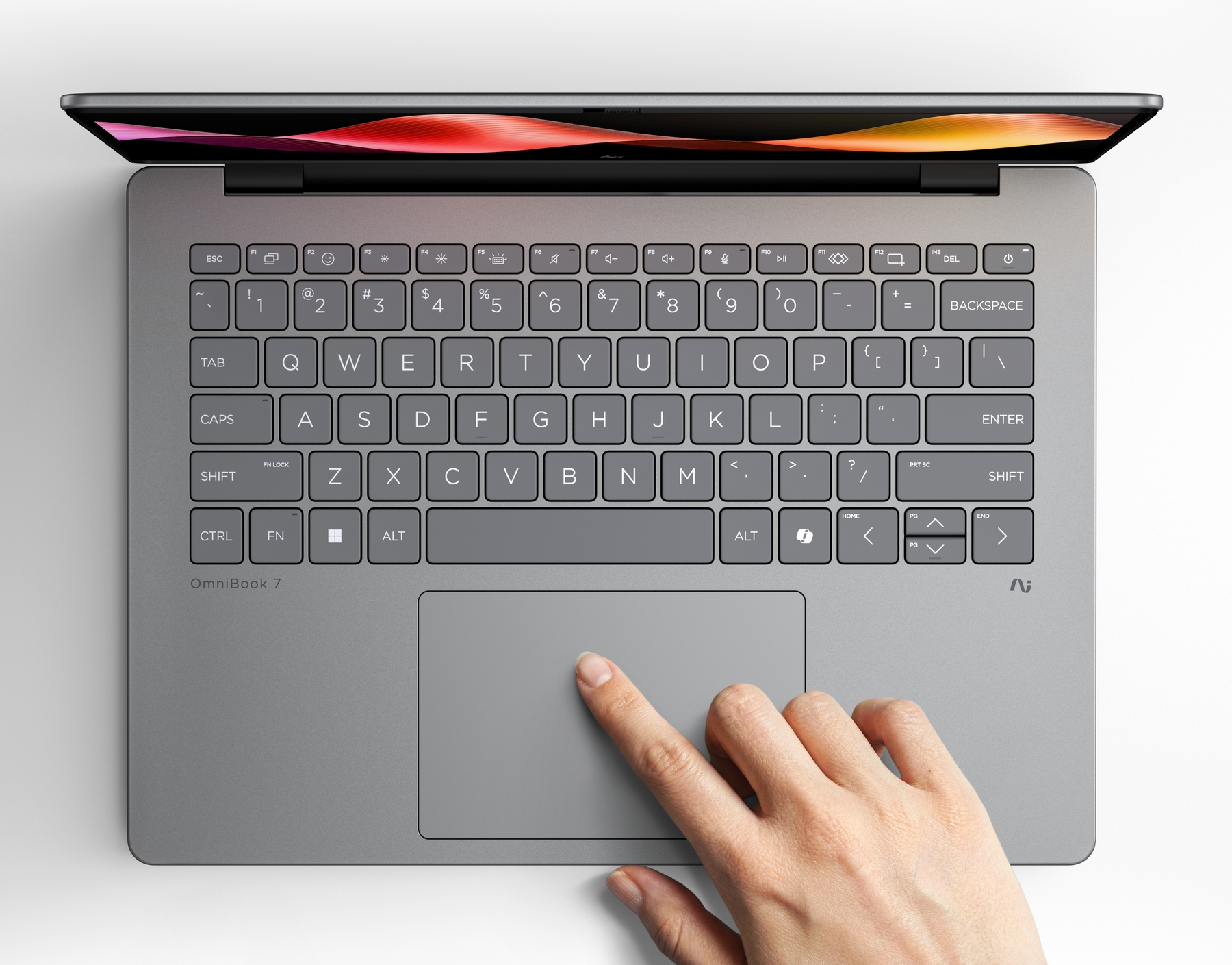 Una mano tocca il touchpad di un laptop grigio aperto con schermo colorato.