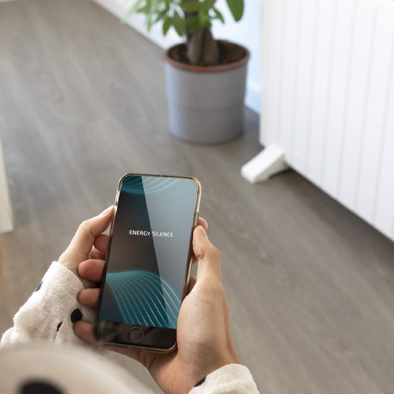 Osoba trzymająca smartfon z napisem "ENERGY SILENCE" i niebieską grafiką.