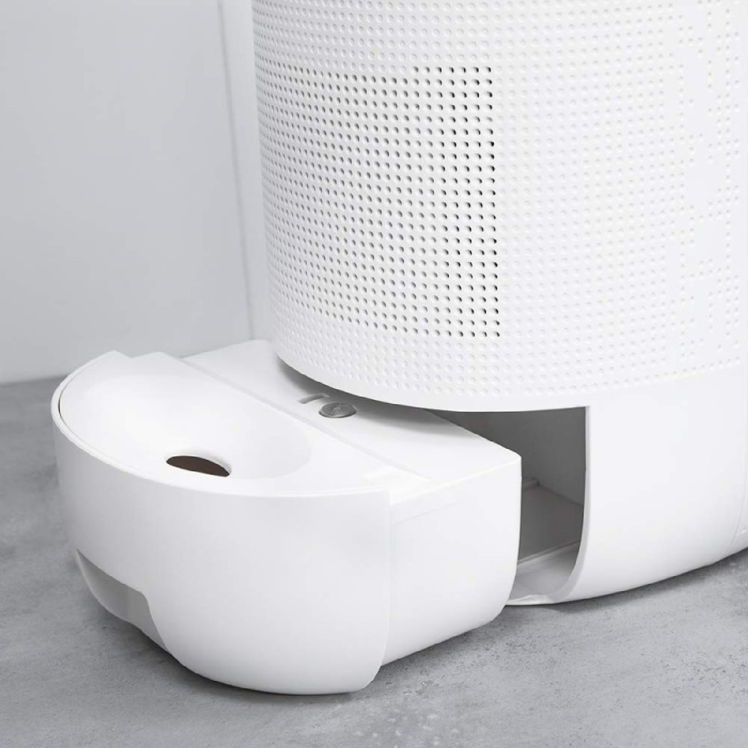 Biały oczyszczacz powietrza z wysuwaną szufladą na szarej powierzchni.