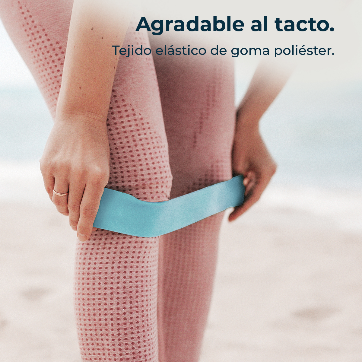 Una donna indossa leggings rosa a pois e tiene un elastico blu.