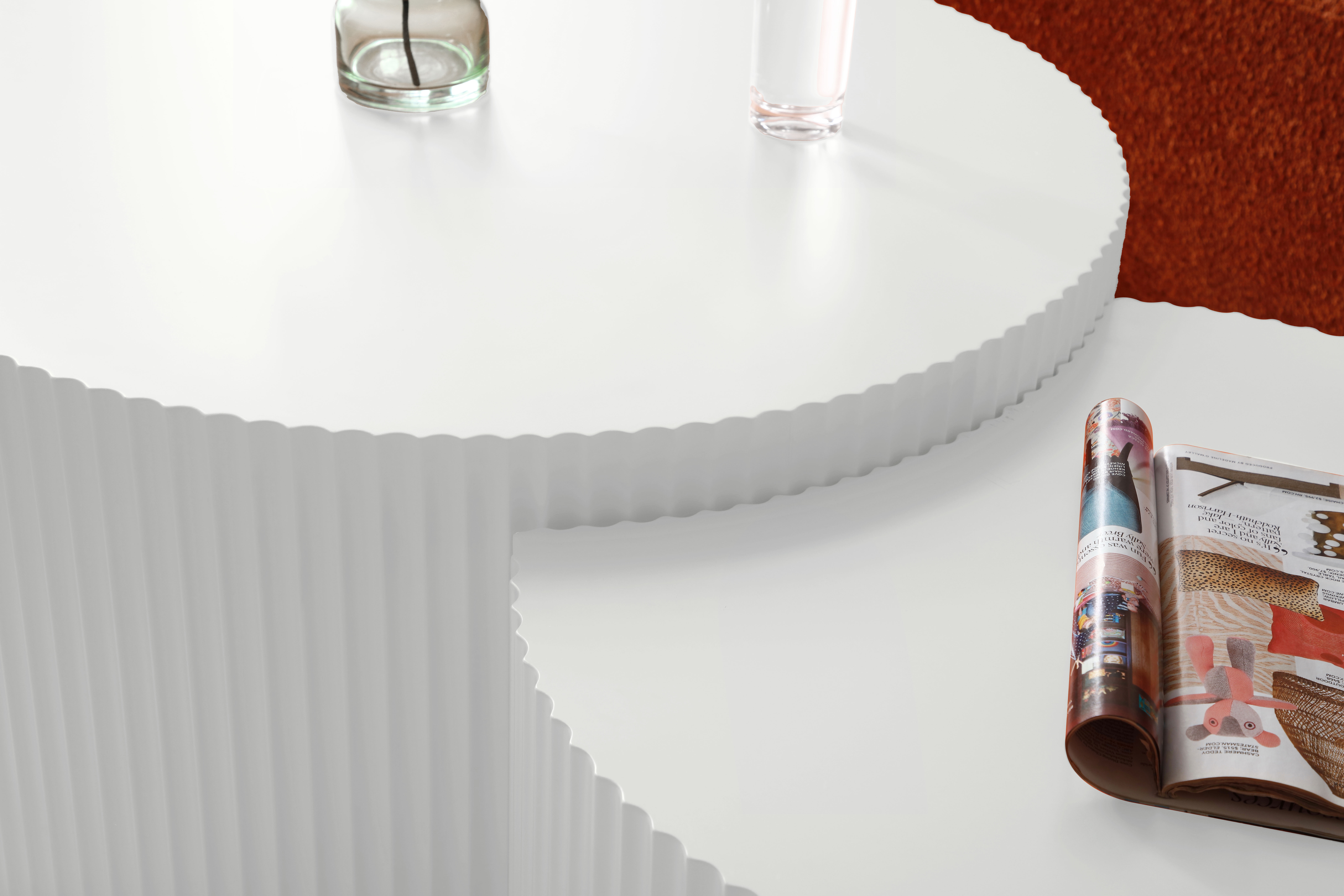 Eine weiße Tischplatte mit geriffelter Kante, einem Glas und einer Zeitschrift.