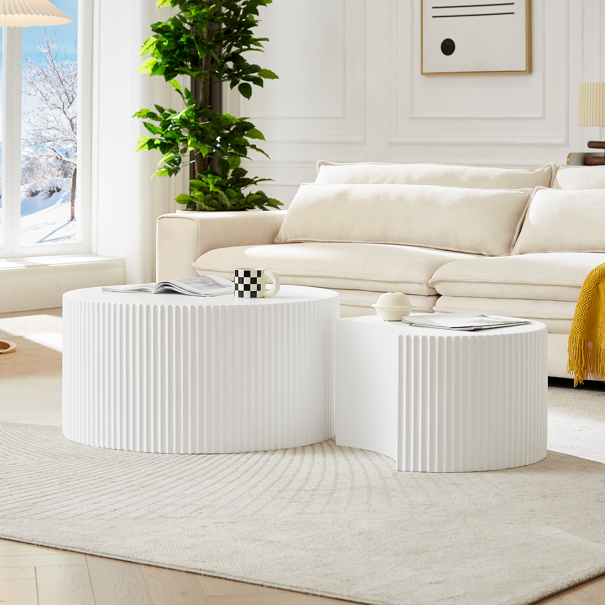Ein helles Wohnzimmer mit einem beigen Sofa, zwei weißen Couchtischen und einem Fenster mit Schnee.