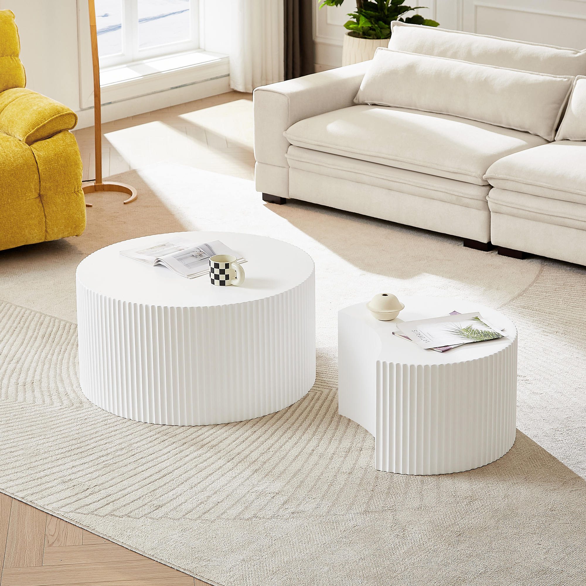 Zwei weiße Beistelltische auf einem Teppich vor einem Sofa und Sessel.