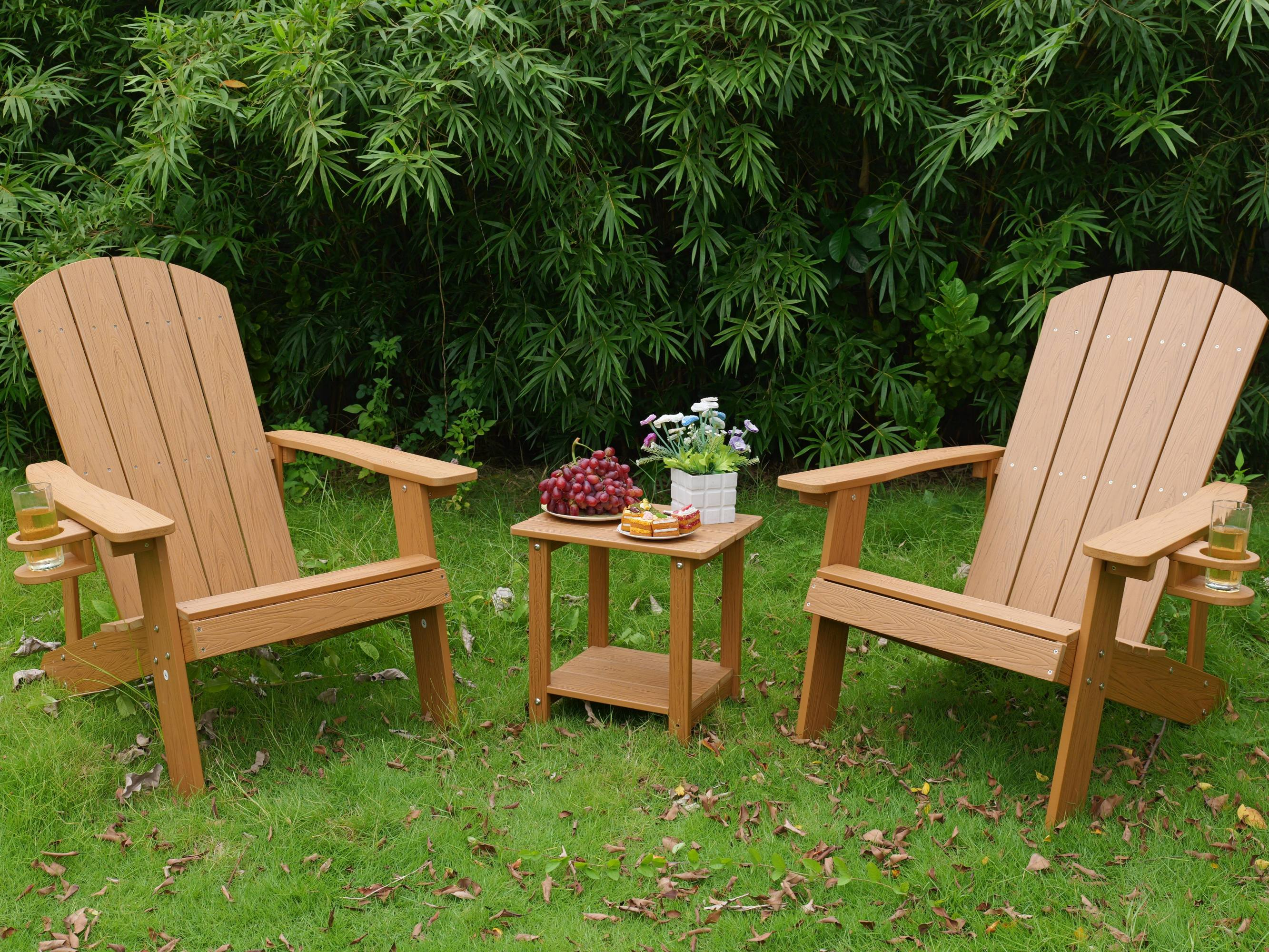 Zwei braune Adirondack-Stühle im Gras, mit einem Beistelltisch dazwischen.