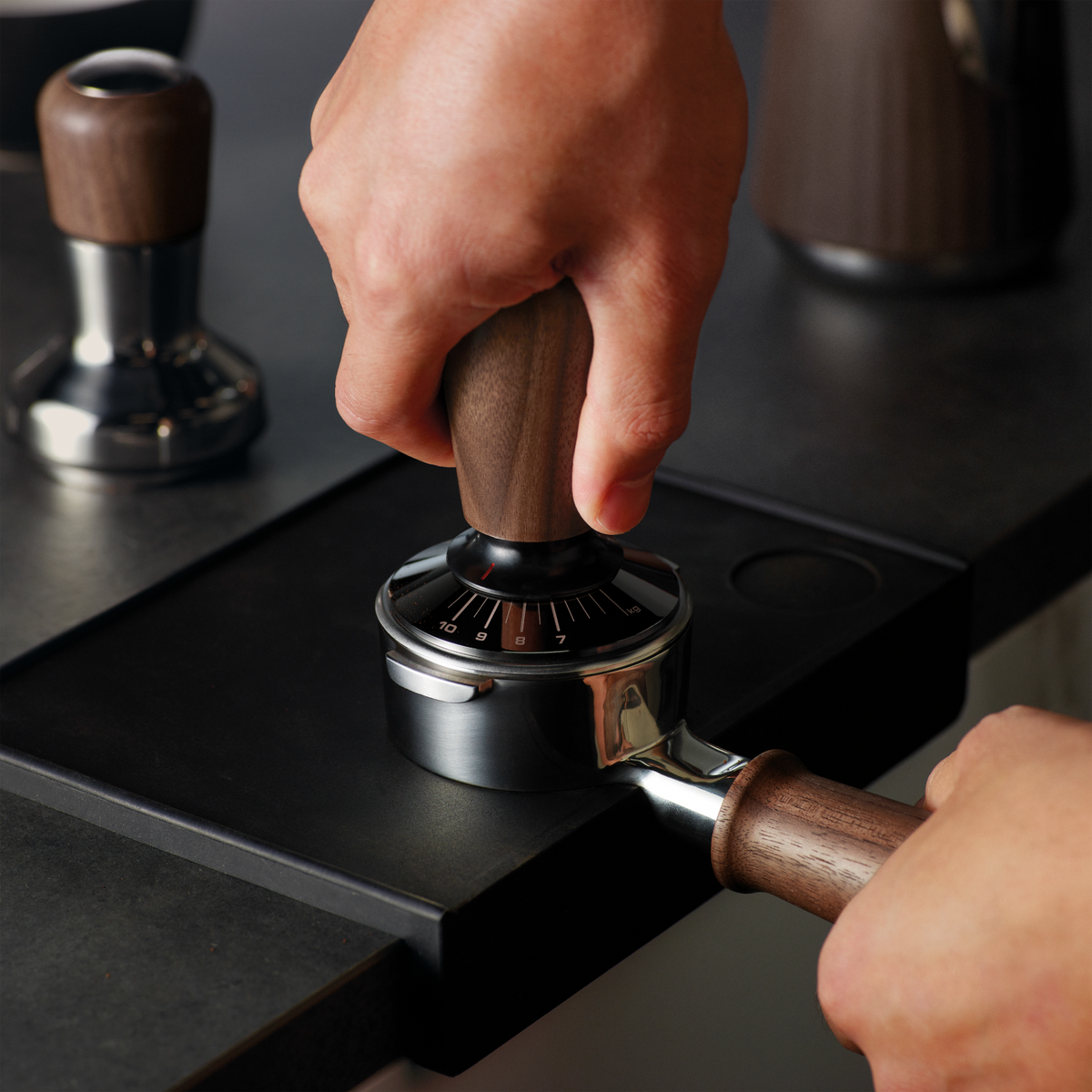 Kaffee-Tamper mit Holzgriff wird auf einer schwarzen Matte verwendet.