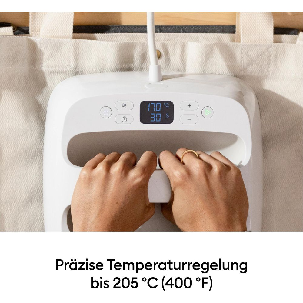 Dos manos sujetan una máquina de plancha térmica con pantalla digital de temperatura y tiempo.