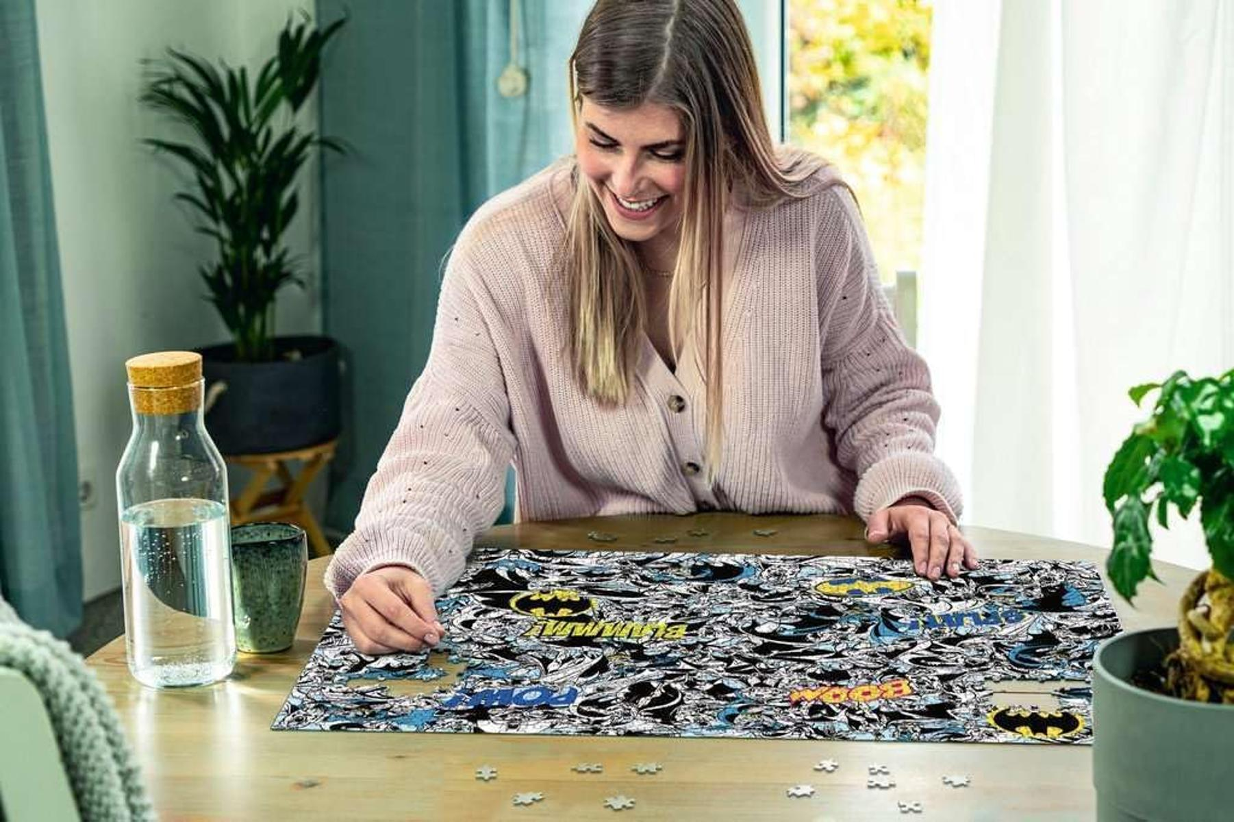Donna che assembla un puzzle di Batman con simboli dei fumetti.