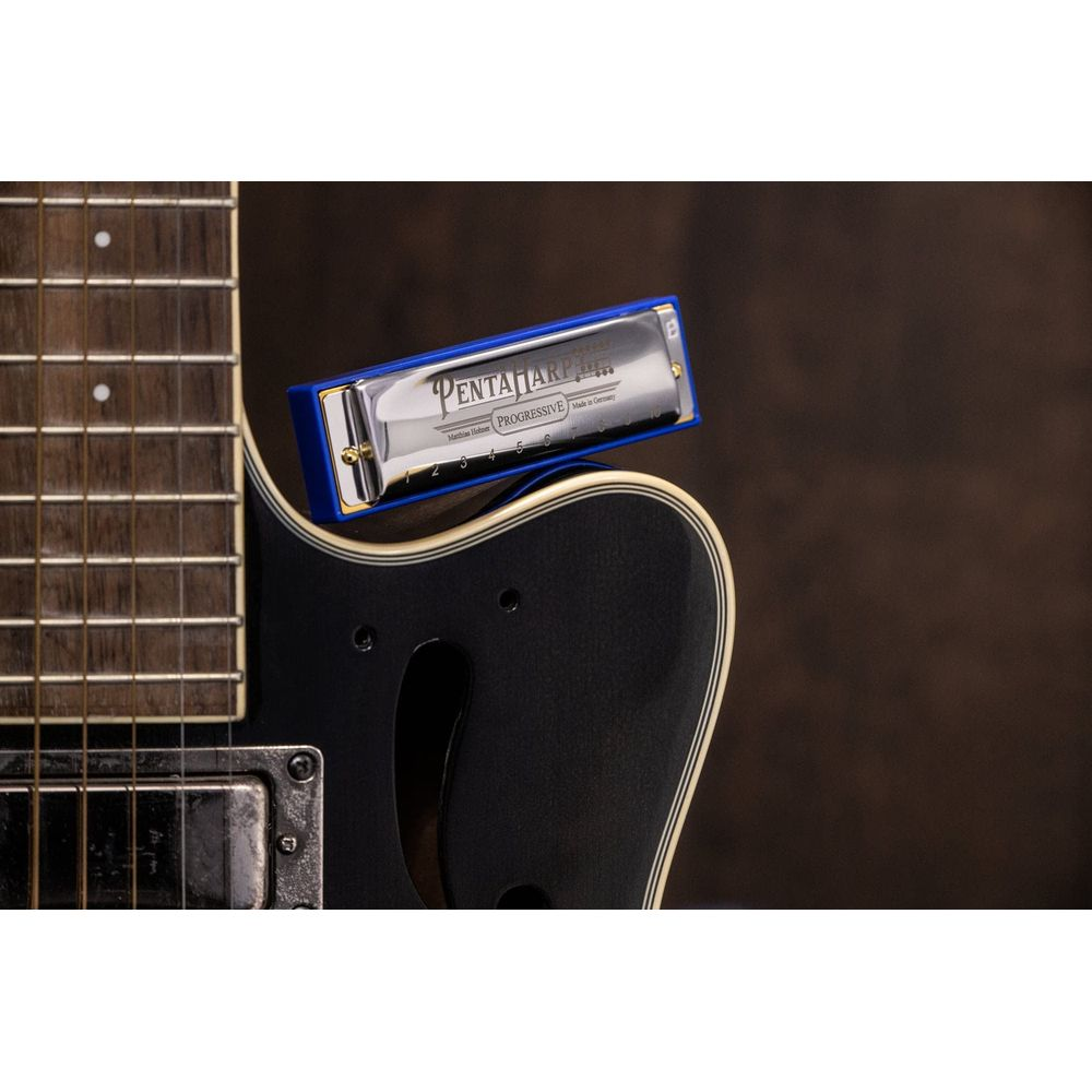 A blue harmonica rests on a black guitar.