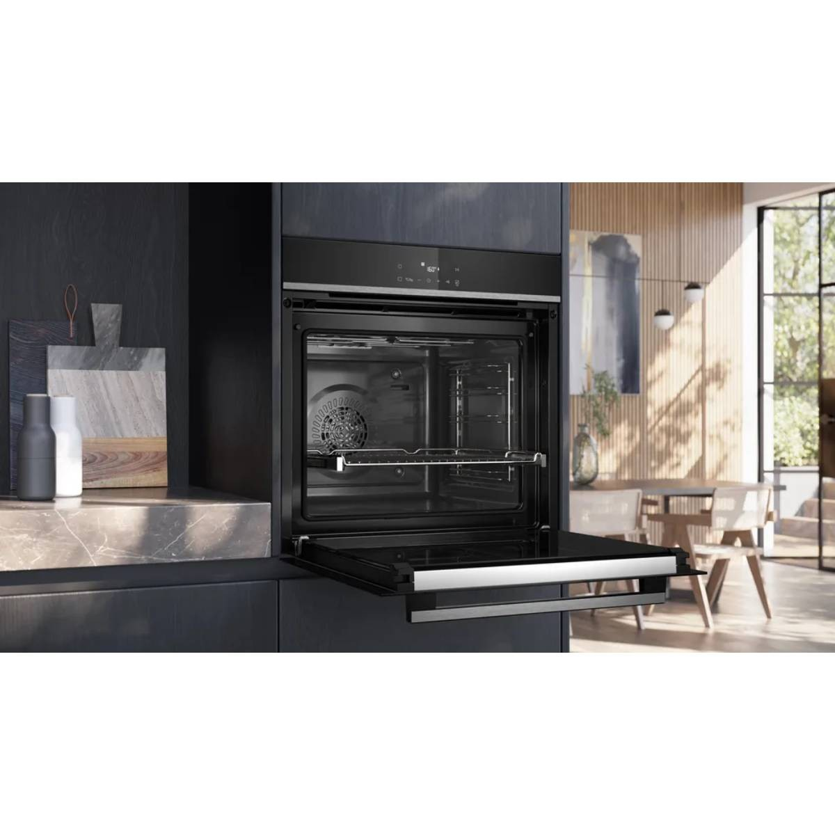 Horno empotrado abierto en cocina moderna con comedor al fondo.