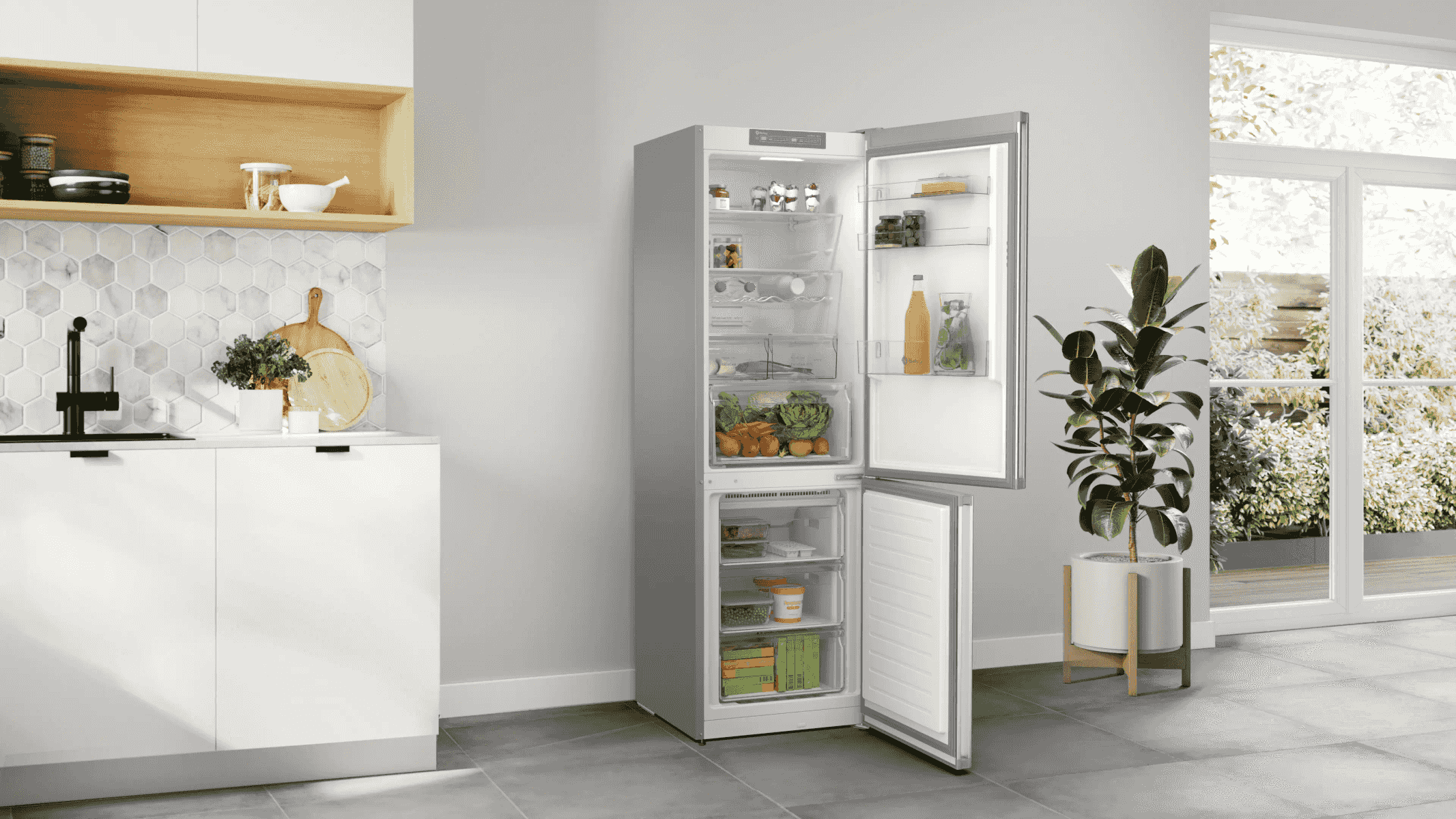 Un refrigerador abierto con comida, junto a una planta y una ventana.