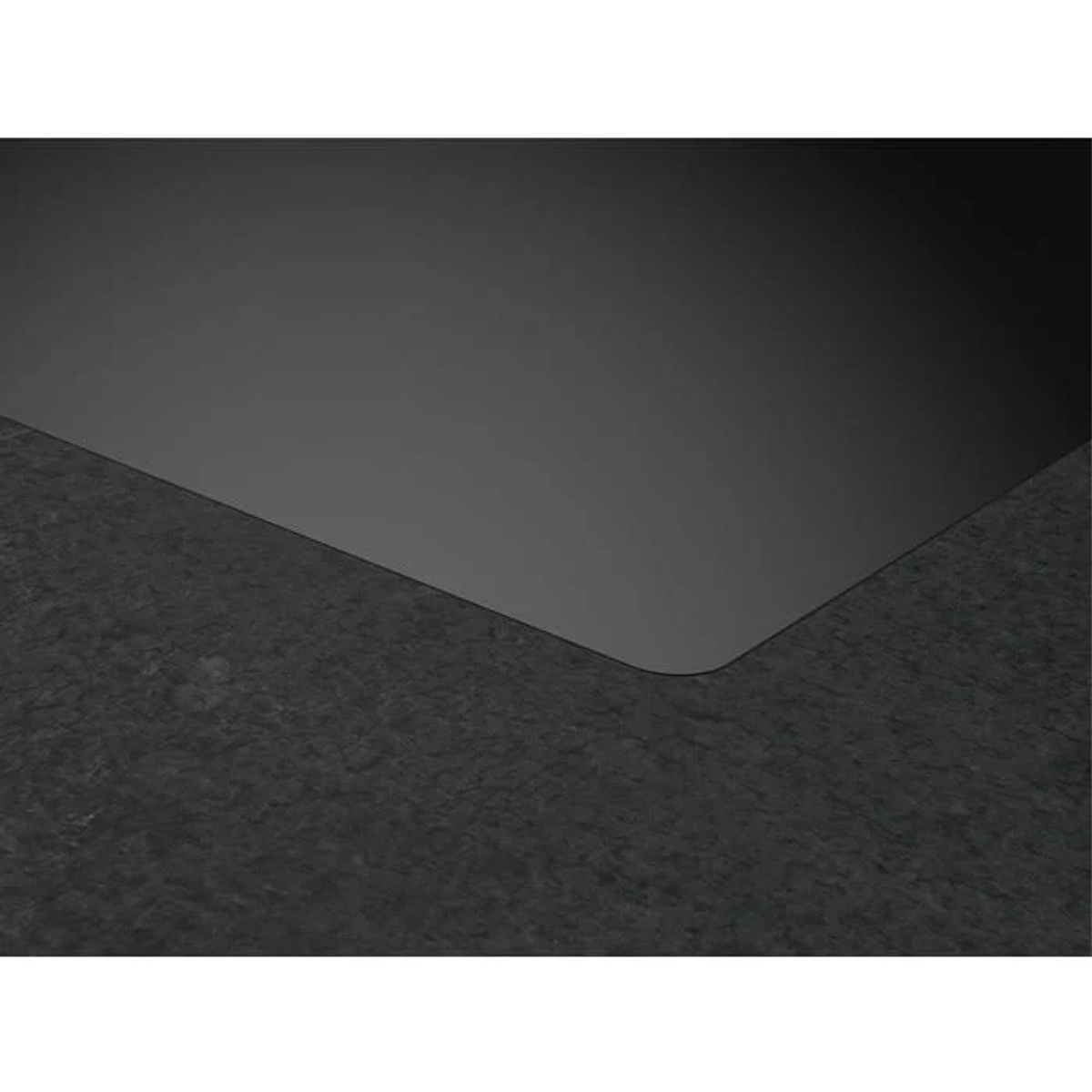 Una superficie texturizada gris oscuro se une a una superficie lisa gris oscuro en una esquina redondeada.