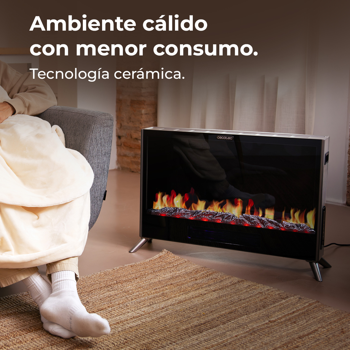 Persona su divano coperta da coperta, seduta davanti a un camino elettrico.