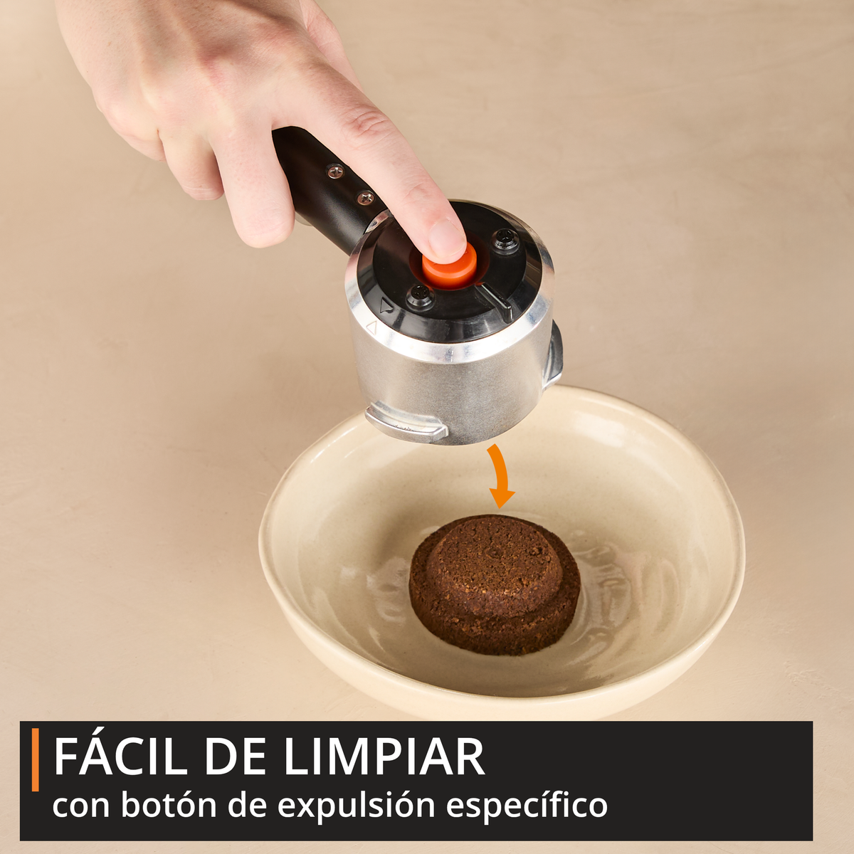 Una mano preme un pulsante per espellere i fondi di caffè da un portafiltro in una ciotola.