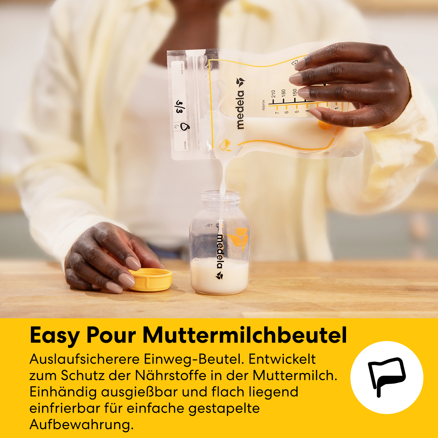 Eine Hand gießt Muttermilch aus einem Beutel in eine Flasche auf einem Holztisch.