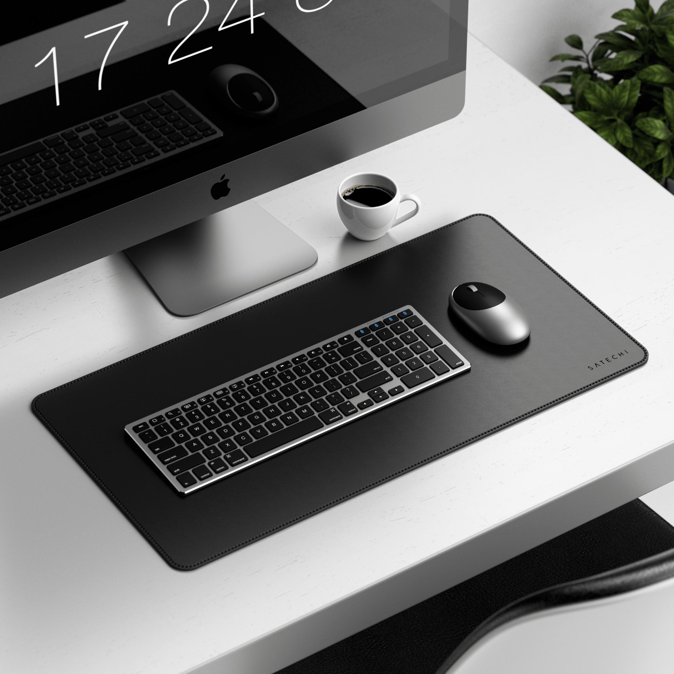 Una scrivania con computer, tastiera, mouse, caffè e pianta.