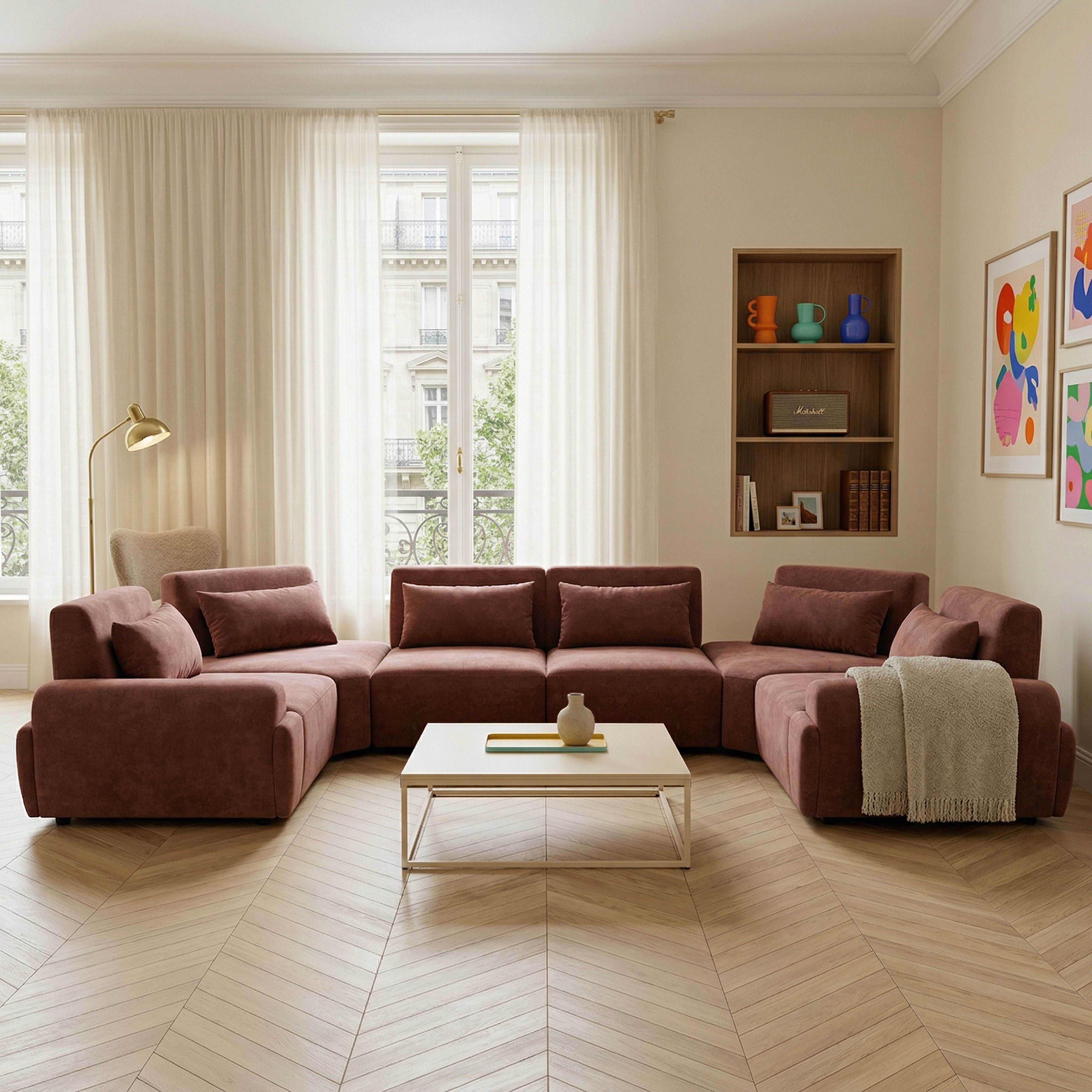 Ein braunes Ecksofa mit Kissen und einer Decke, vor einem Fenster mit Vorhängen.