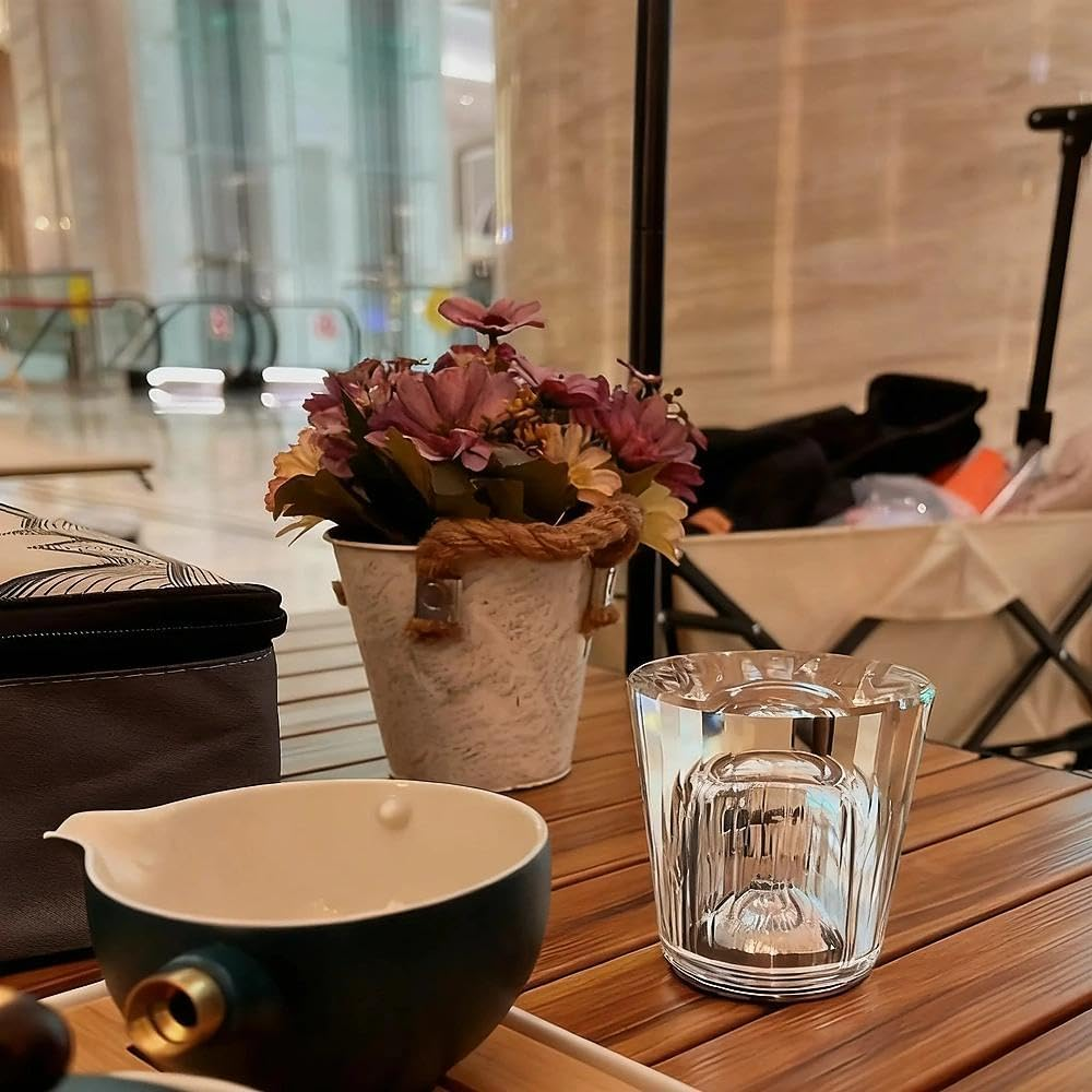 Ein Glas Wasser und eine Schale mit Blumen stehen auf einem Holztisch.