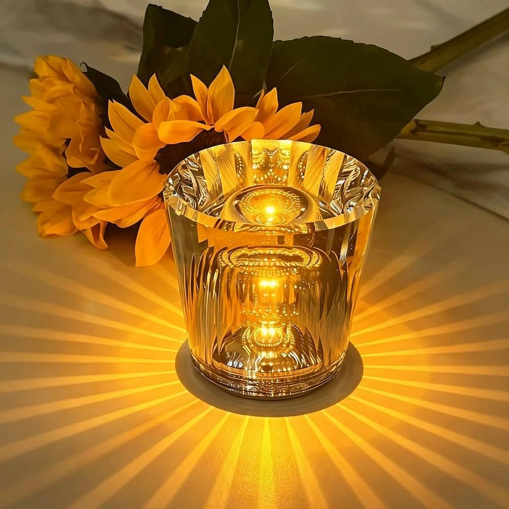 Ein Glas mit Kerzenlicht wirft helle Muster neben Sonnenblumen.