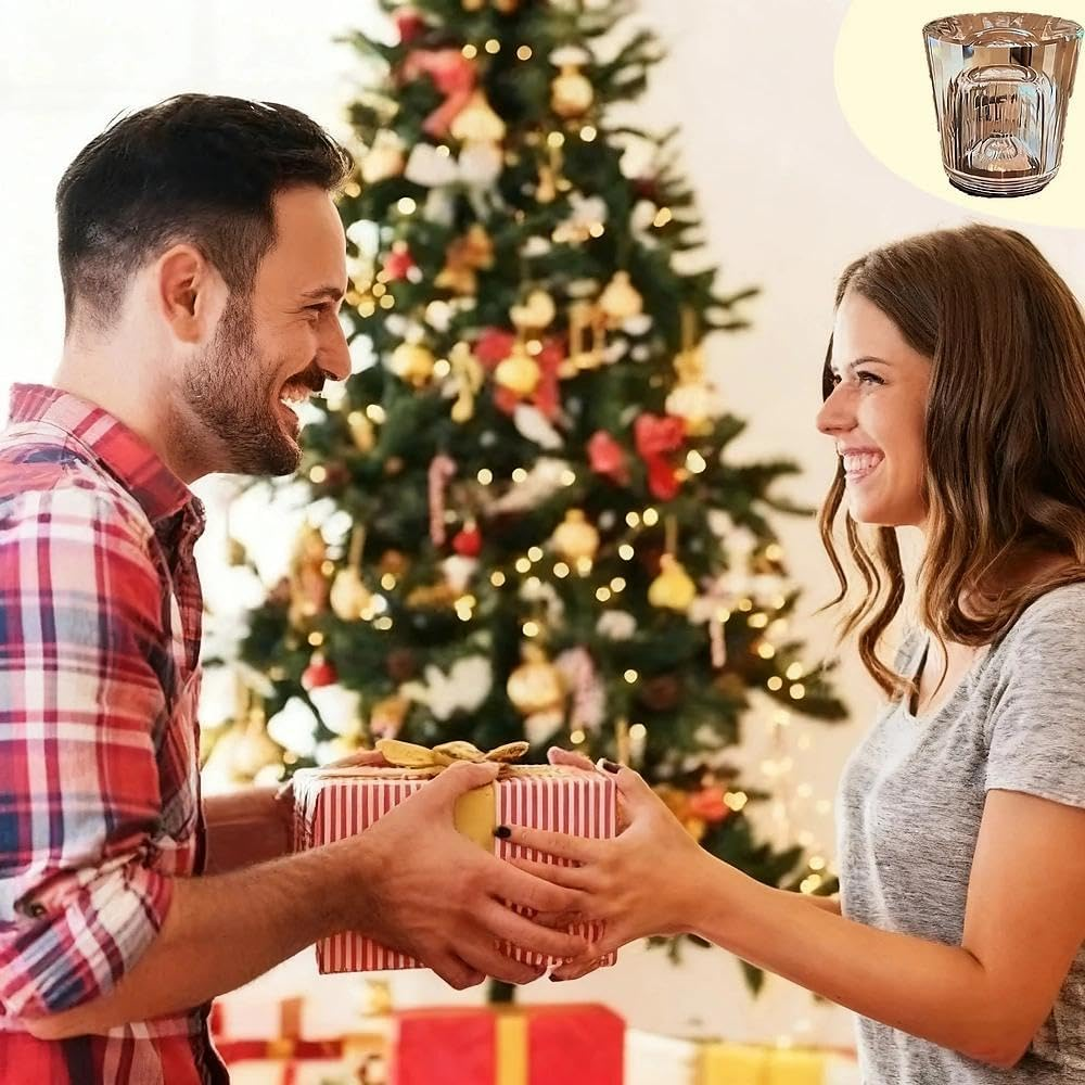 Mann übergibt Frau Geschenk vor Weihnachtsbaum. Glas oben rechts.