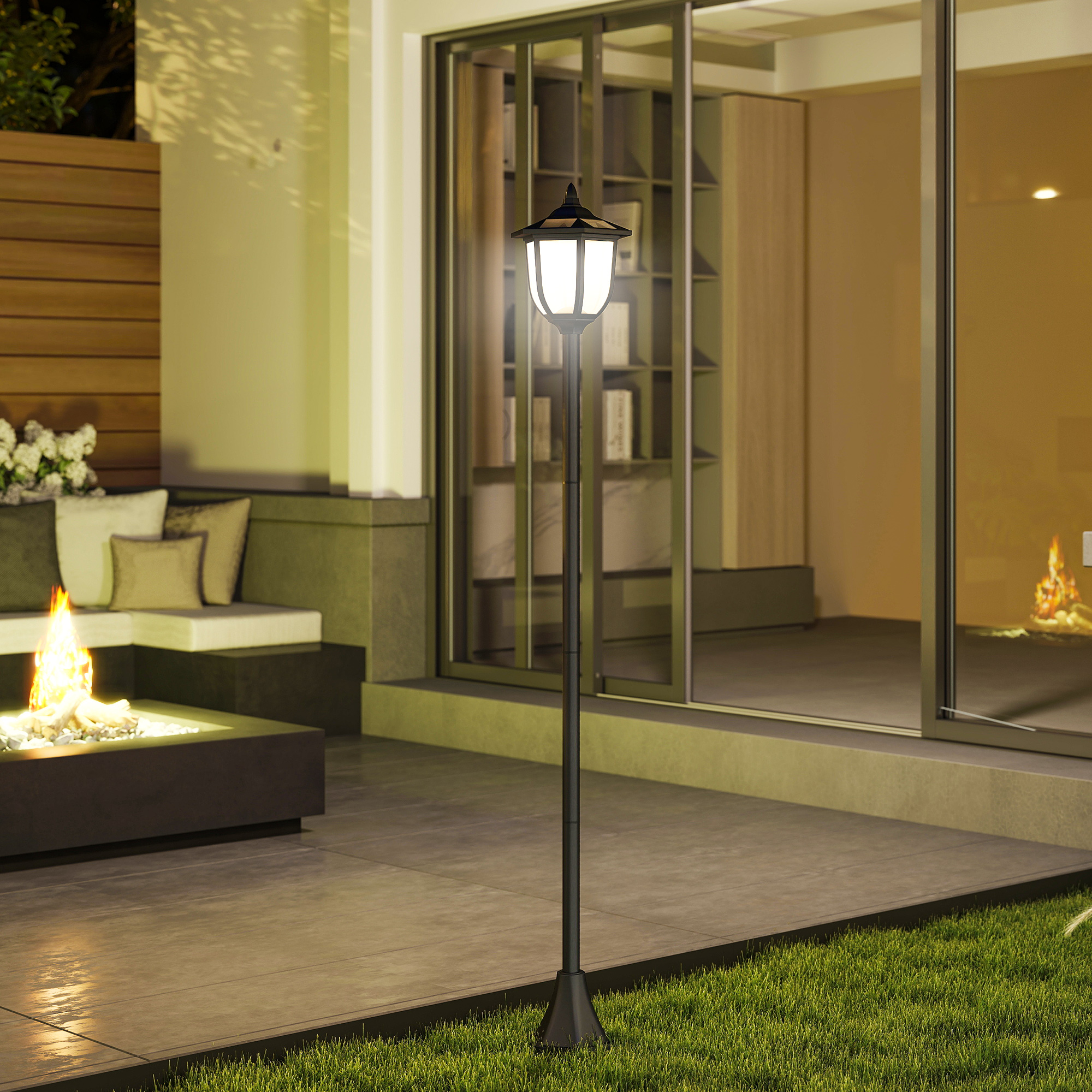 Un poste de luz exterior encendido se encuentra en un patio junto a una hoguera y asientos al aire libre.