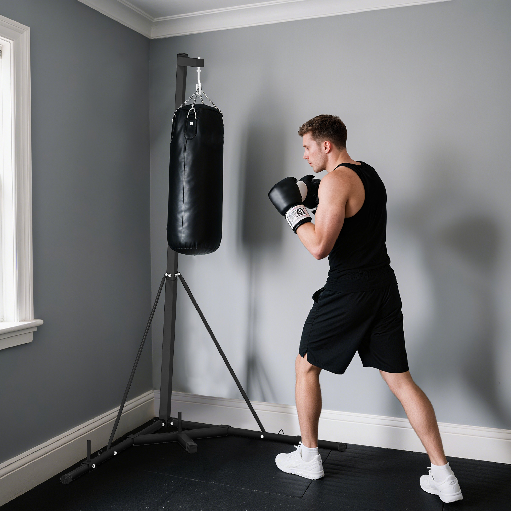Un hombre con guantes de boxeo entrena en un saco de boxeo en una habitación con paredes grises.