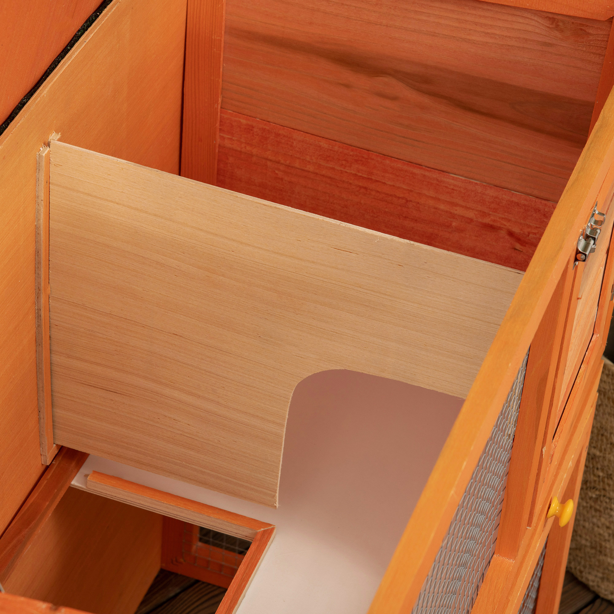Interior de madera de un gallinero naranja con un paso.