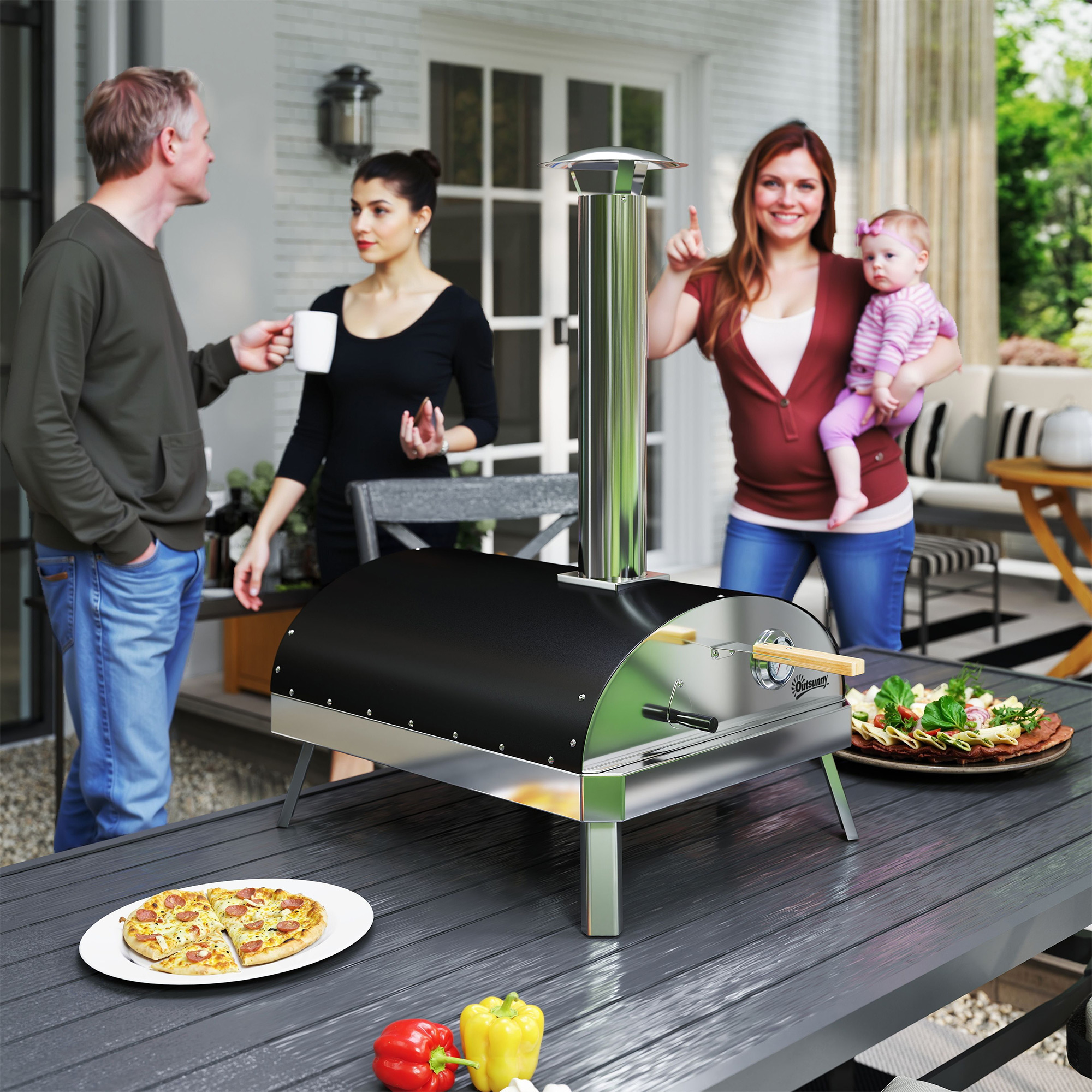 Familia disfrutando de pizza y bebidas al aire libre junto a un horno de pizza.
