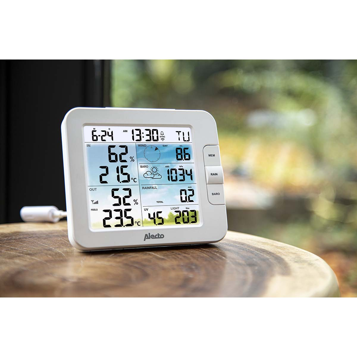 Ein weißes digitales Wetterstation zeigt Zeit, Temperatur, Luftfeuchtigkeit, Wind und Regen.