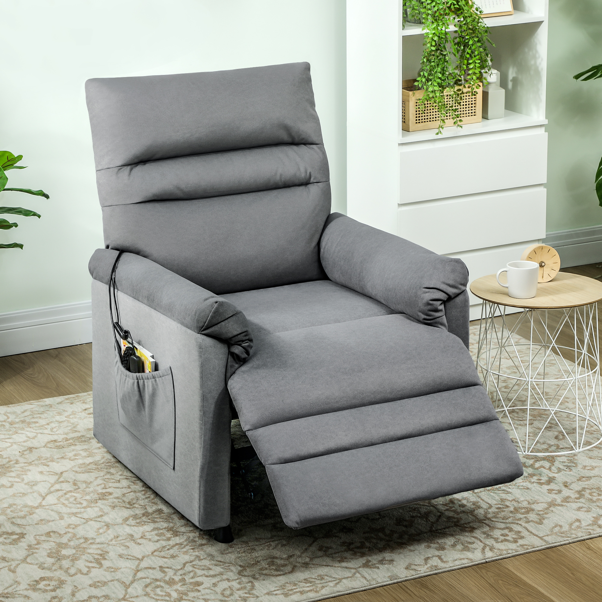 Un sillón reclinable gris con reposapiés extendido está sobre una alfombra estampada.