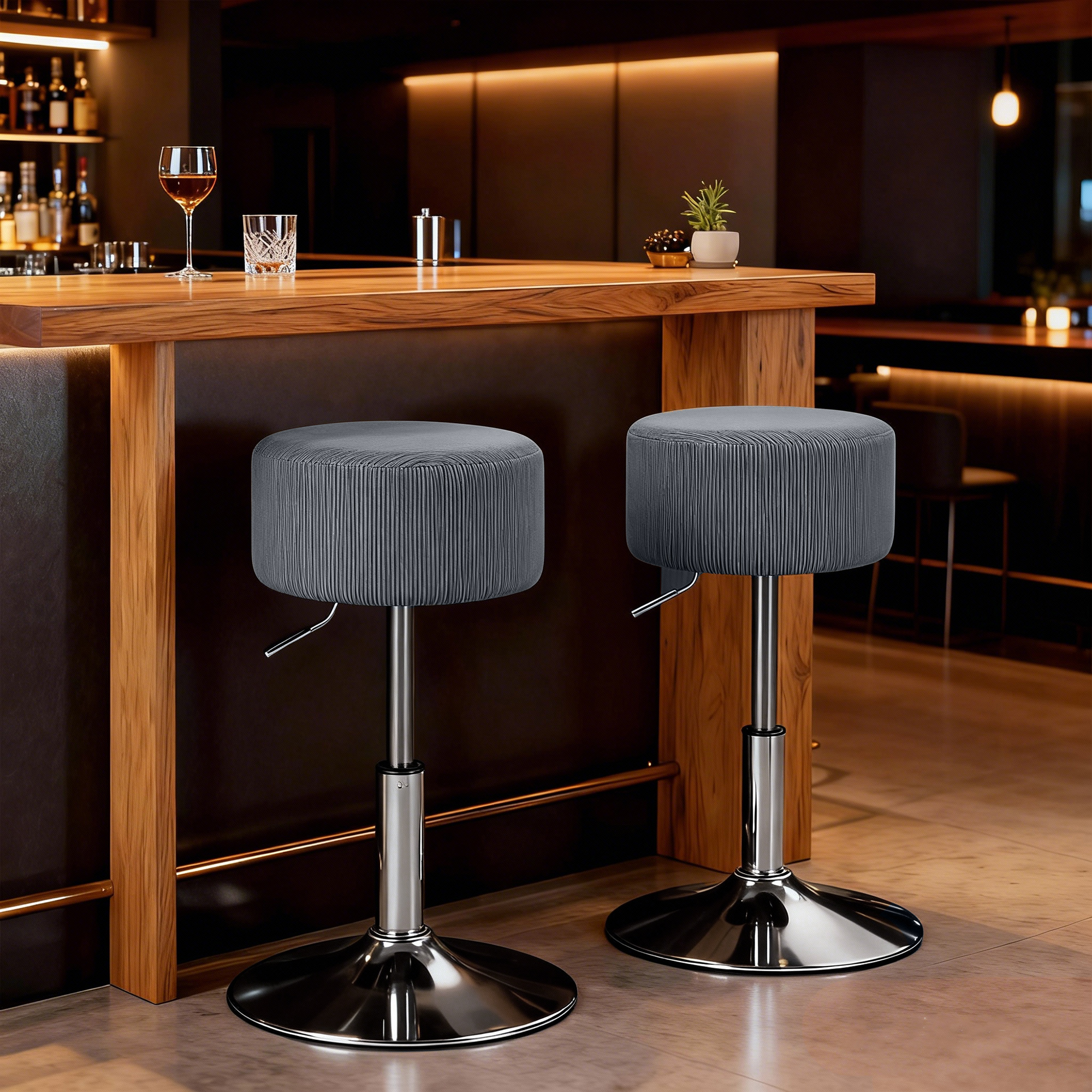 Dos taburetes de bar grises con bases cromadas están frente a un mostrador de madera.