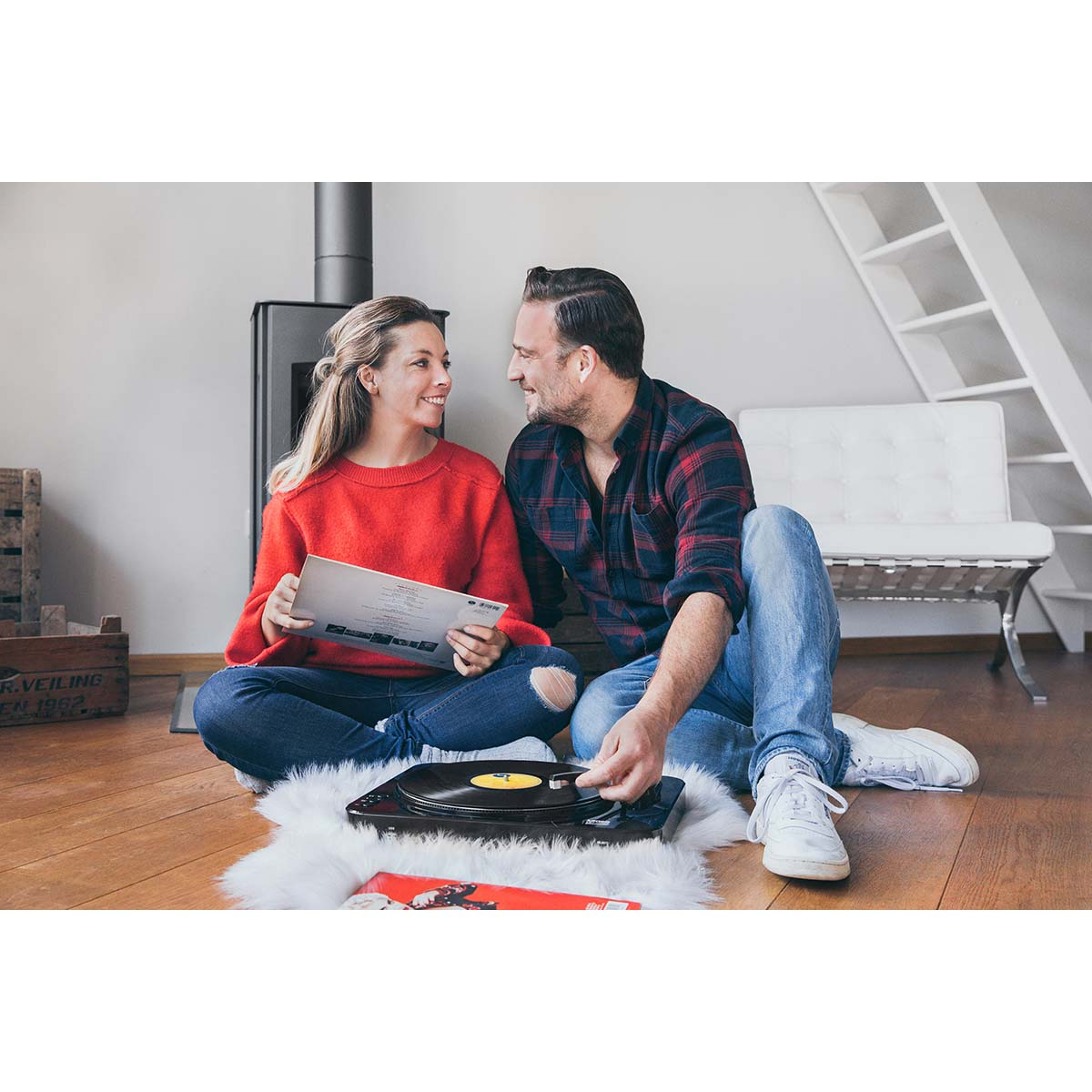 Para siedzi na podłodze, słuchając płyt z gramofonem.