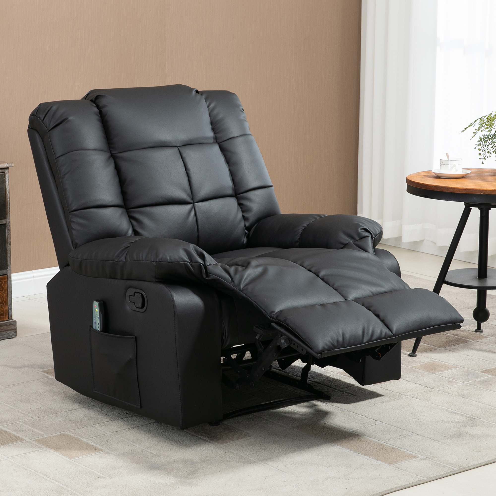 Tumbona de cuero sintético negro con reposapiés extendido, control remoto y bolsillo.