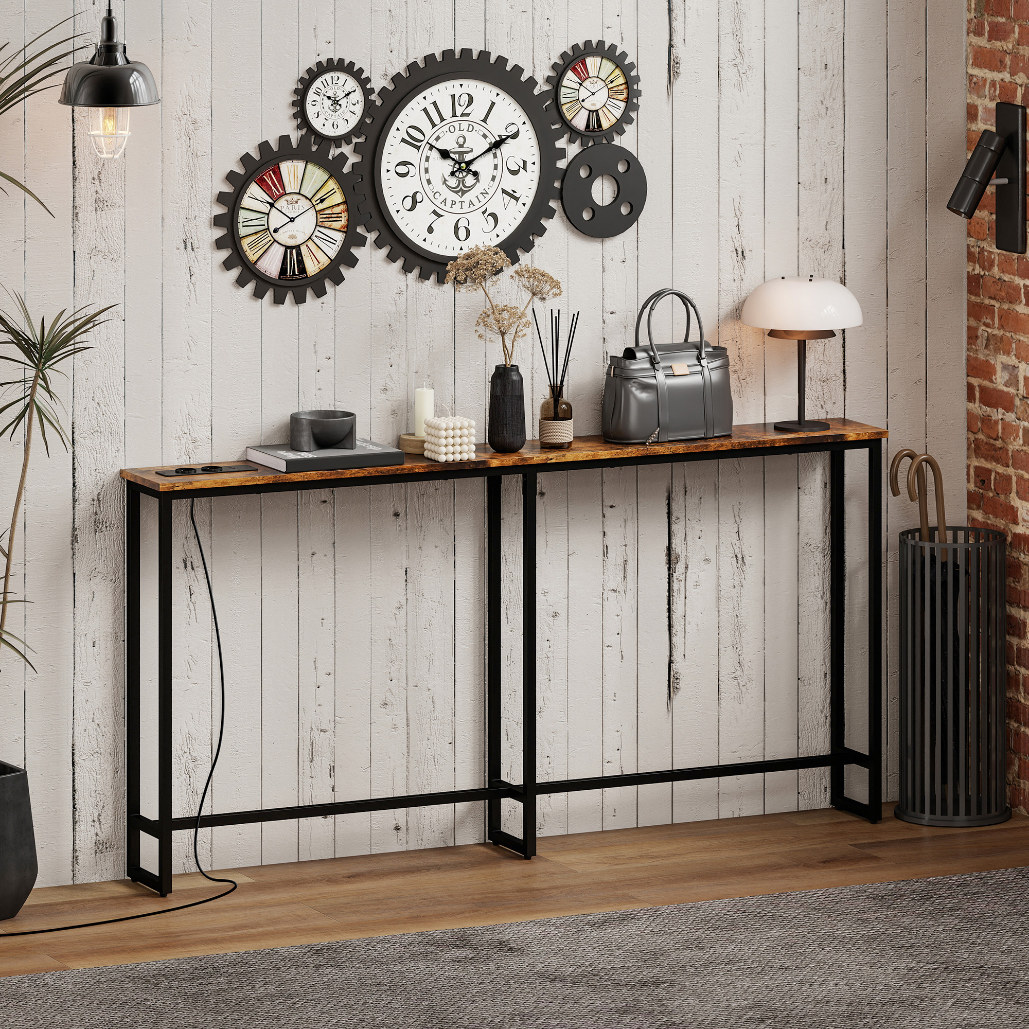 Relojes de pared decorativos sobre una mesa consola estrecha con lámpara, bolso y jarrón.