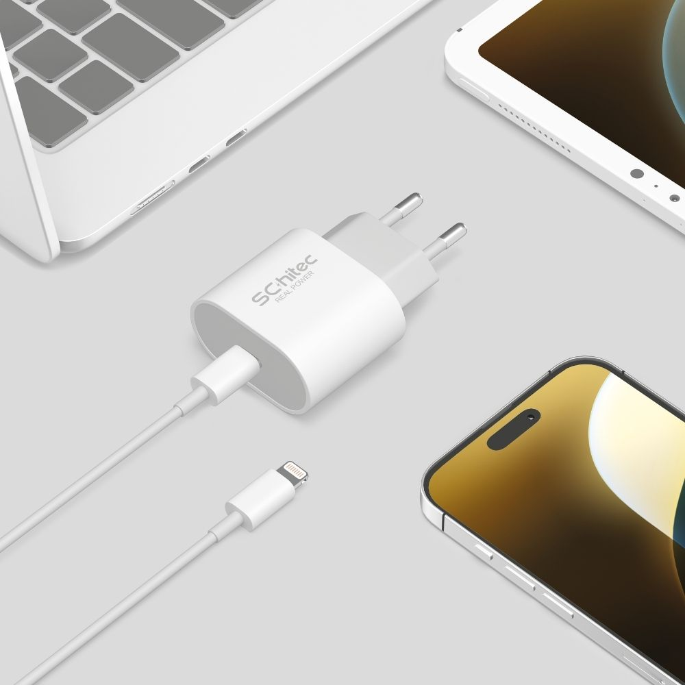 Kablolu beyaz güç adaptörü, dizüstü bilgisayar ve tabletin yanında akıllı telefon şarj ediyor.