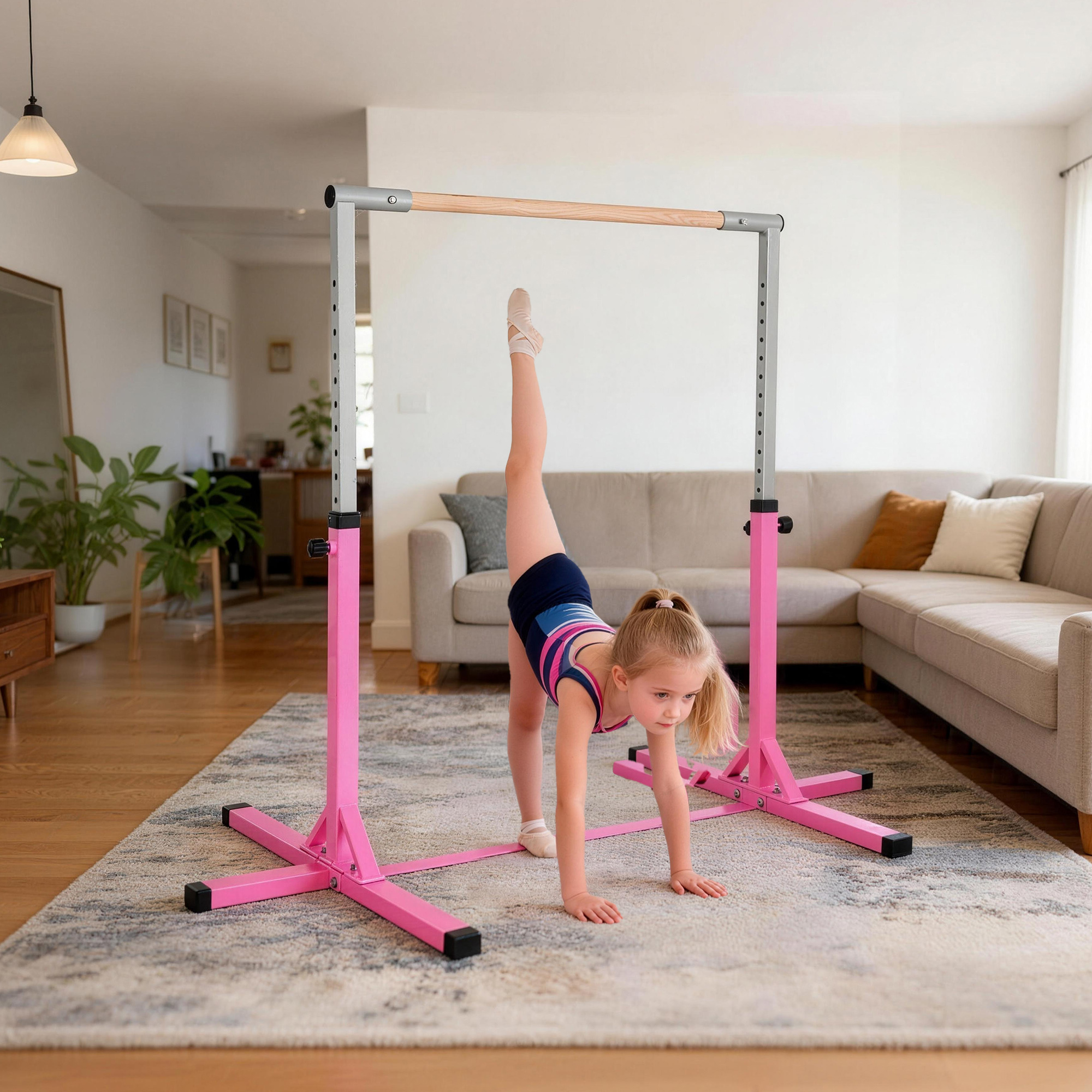 Una niña con traje de gimnasia practica un estiramiento en una barra de ballet rosa en una sala.