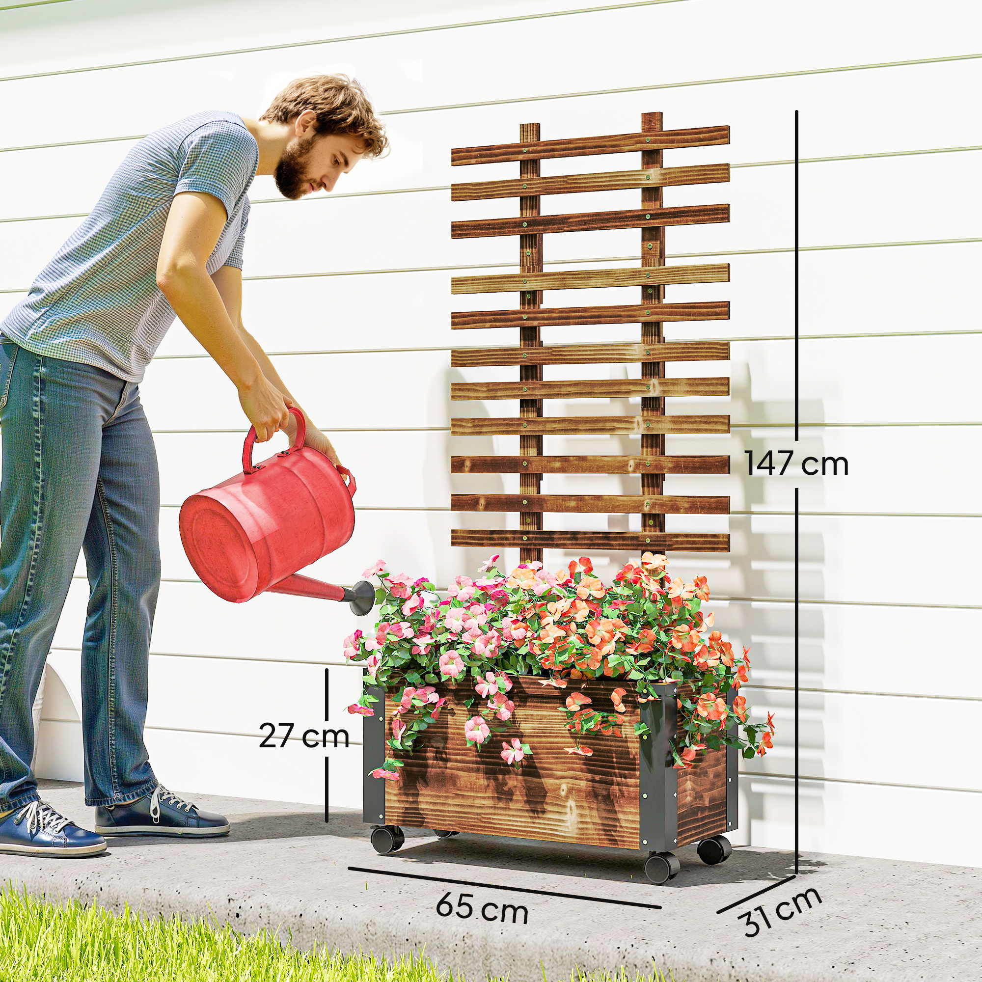 Hombre regando flores en jardinera de madera con enrejado junto a una casa.
