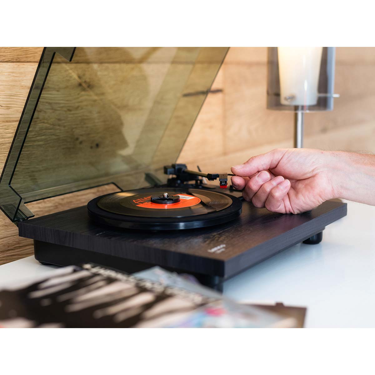 Ręka opuszcza igłę na płytę winylową na gramofonie.