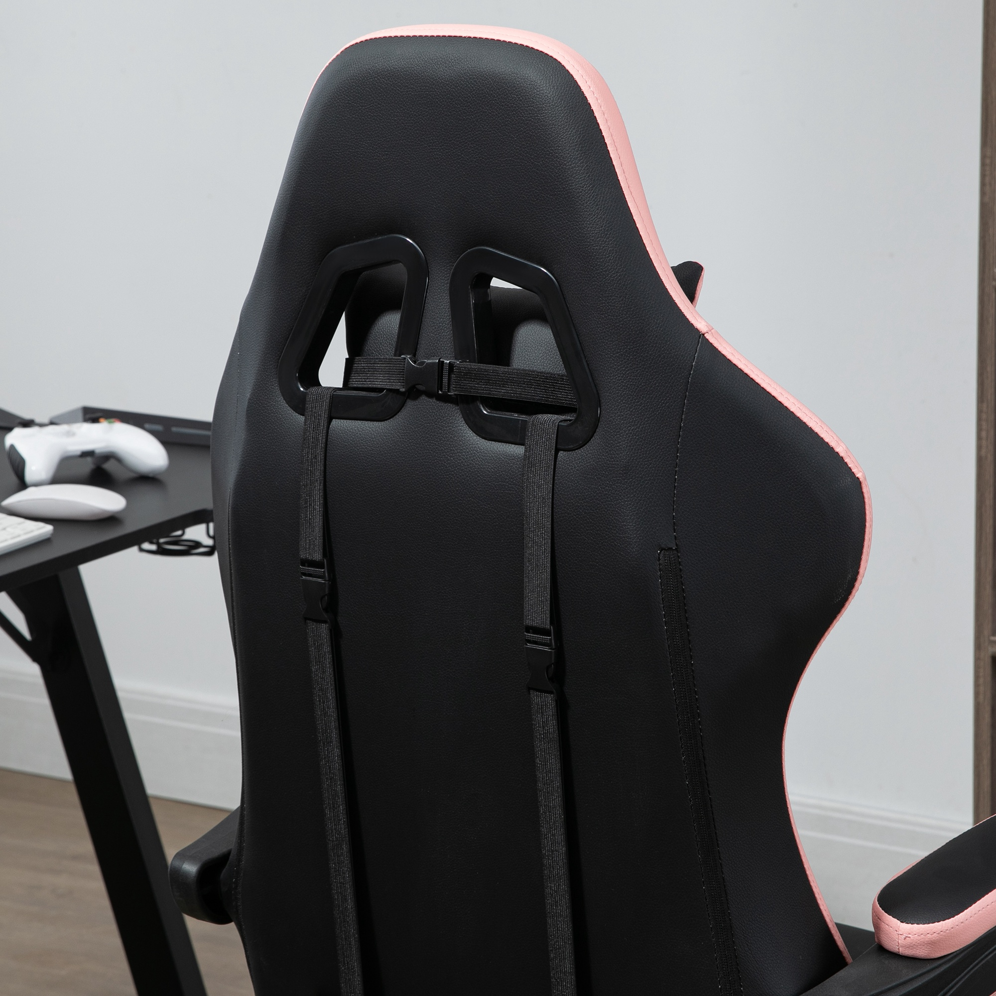 Silla gaming negra con ribete rosa y reposacabezas, vista de cerca.