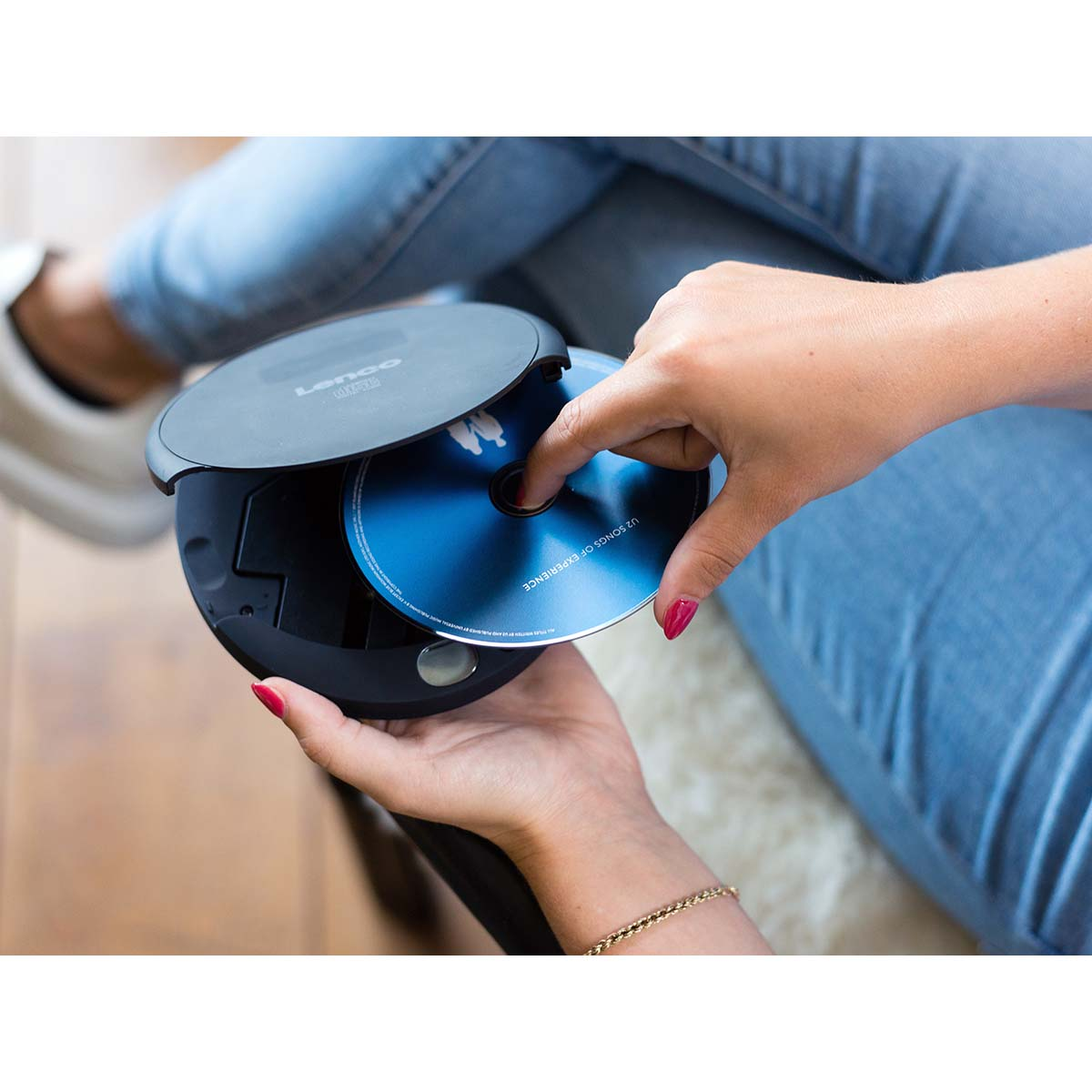 Kobieta wkłada płytę CD do przenośnego odtwarzacza CD.