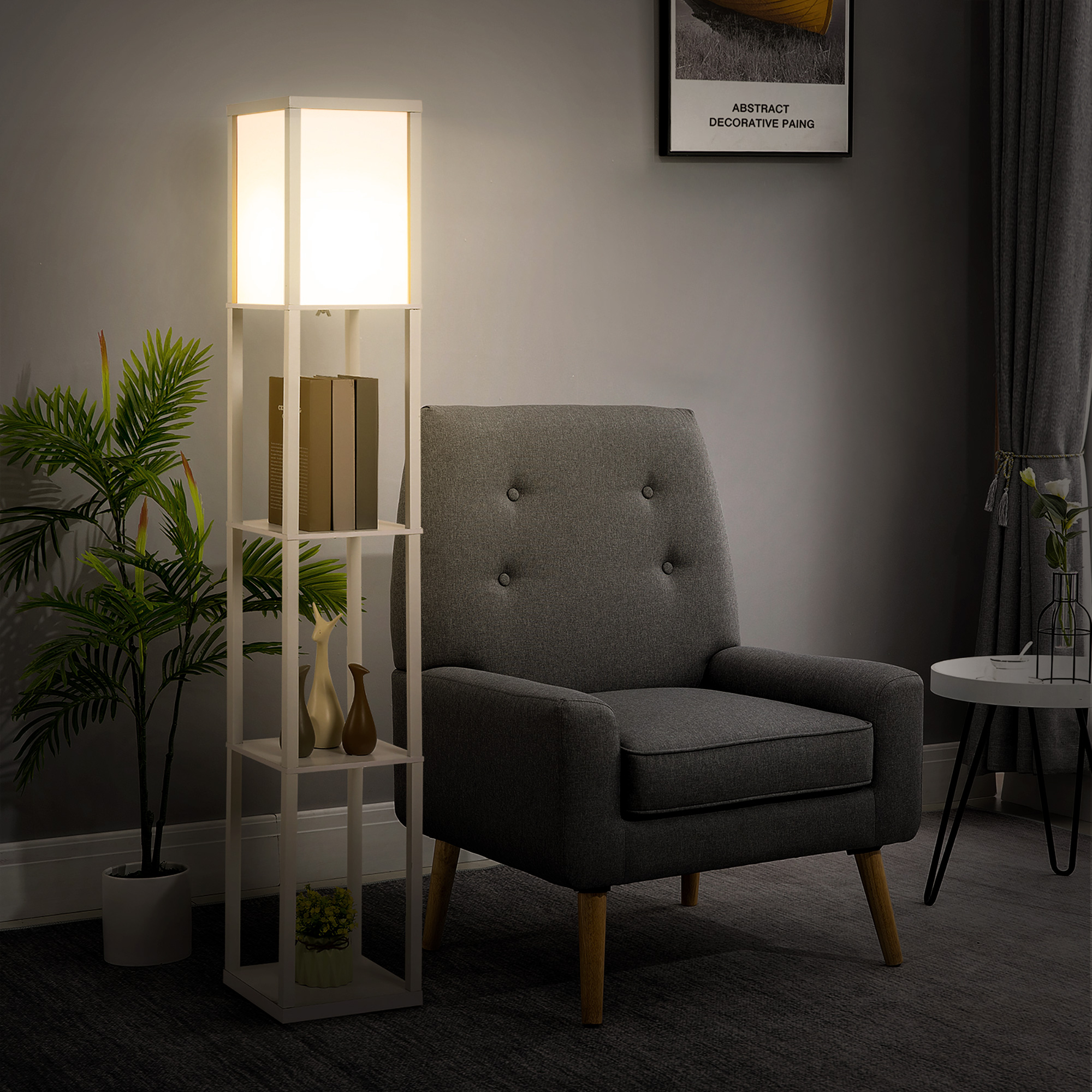 Estantería con lámpara de pie, libros y jarrones junto a un sillón gris.