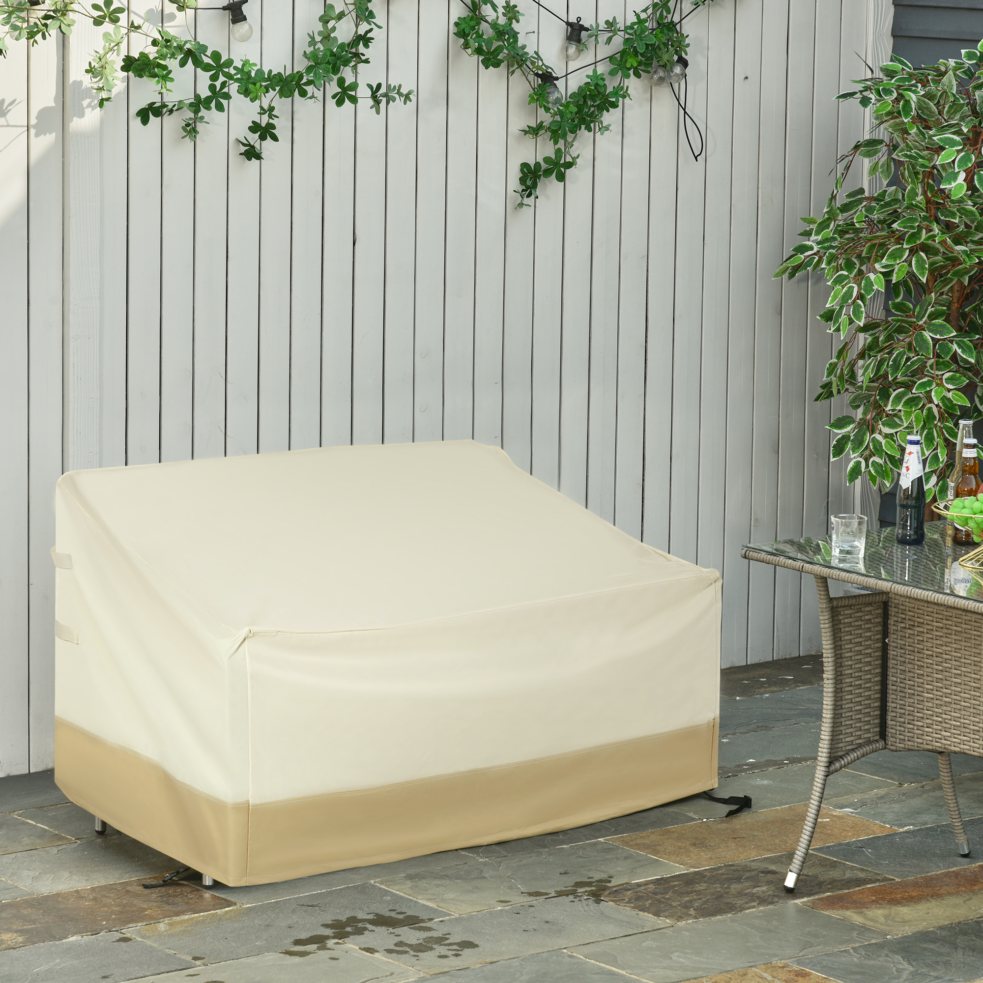 Una funda beige protege muebles de exterior contra una pared de madera blanca.