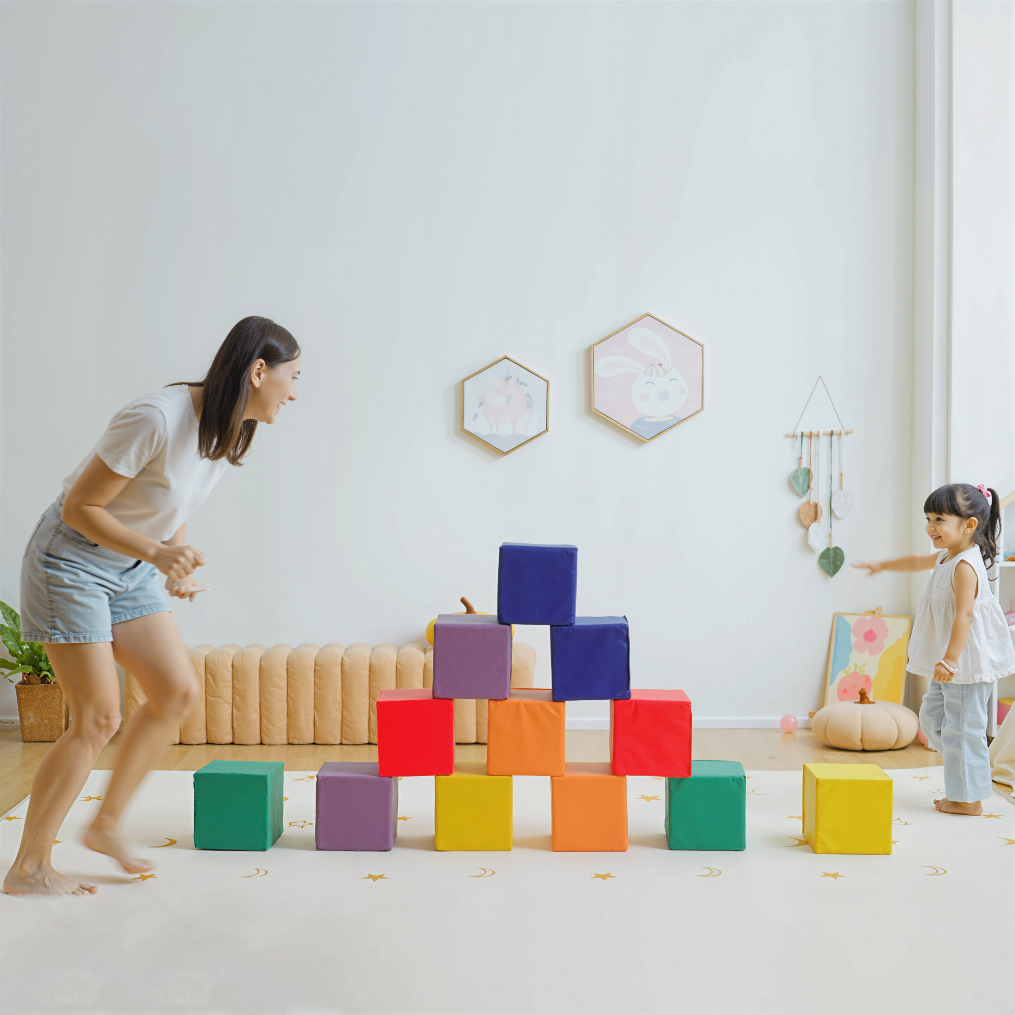 Mujer y niño construyendo con bloques coloridos en una habitación luminosa.