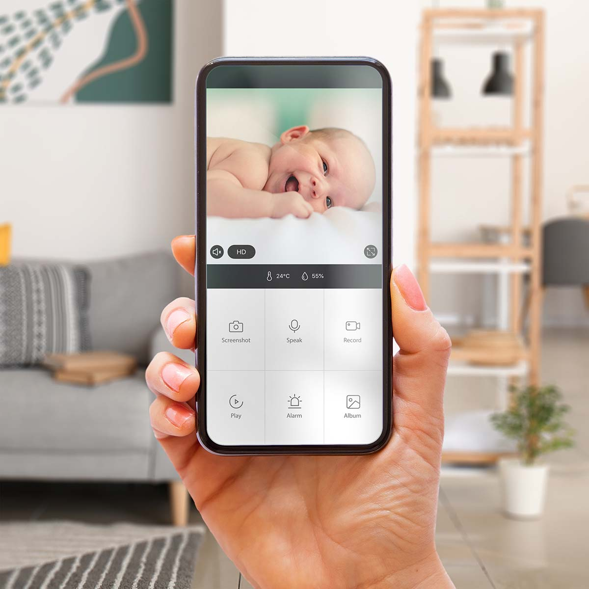 Hand hält Smartphone mit Babyüberwachung: lächelndes Baby, Temperatur 24°C, Luftfeuchtigkeit 55%.