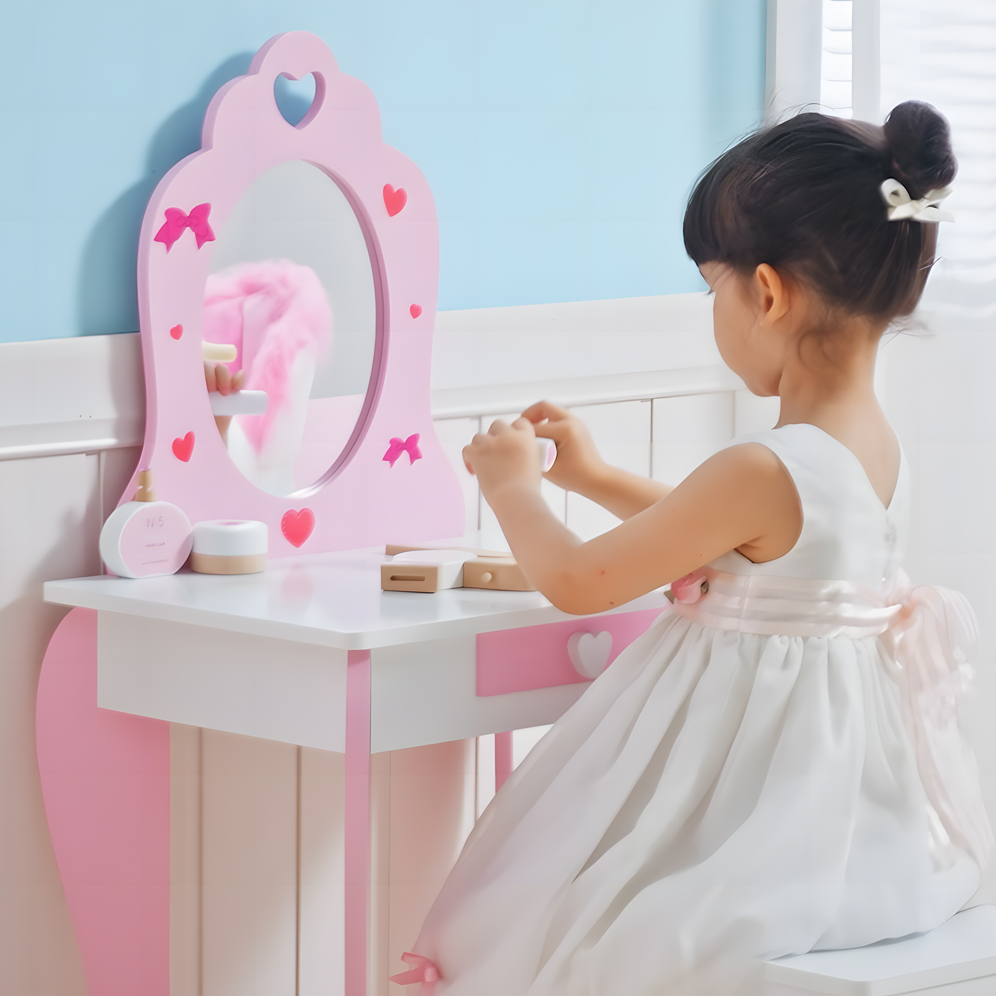 Una niña con vestido blanco se sienta en un tocador rosa, jugando con maquillaje de juguete.