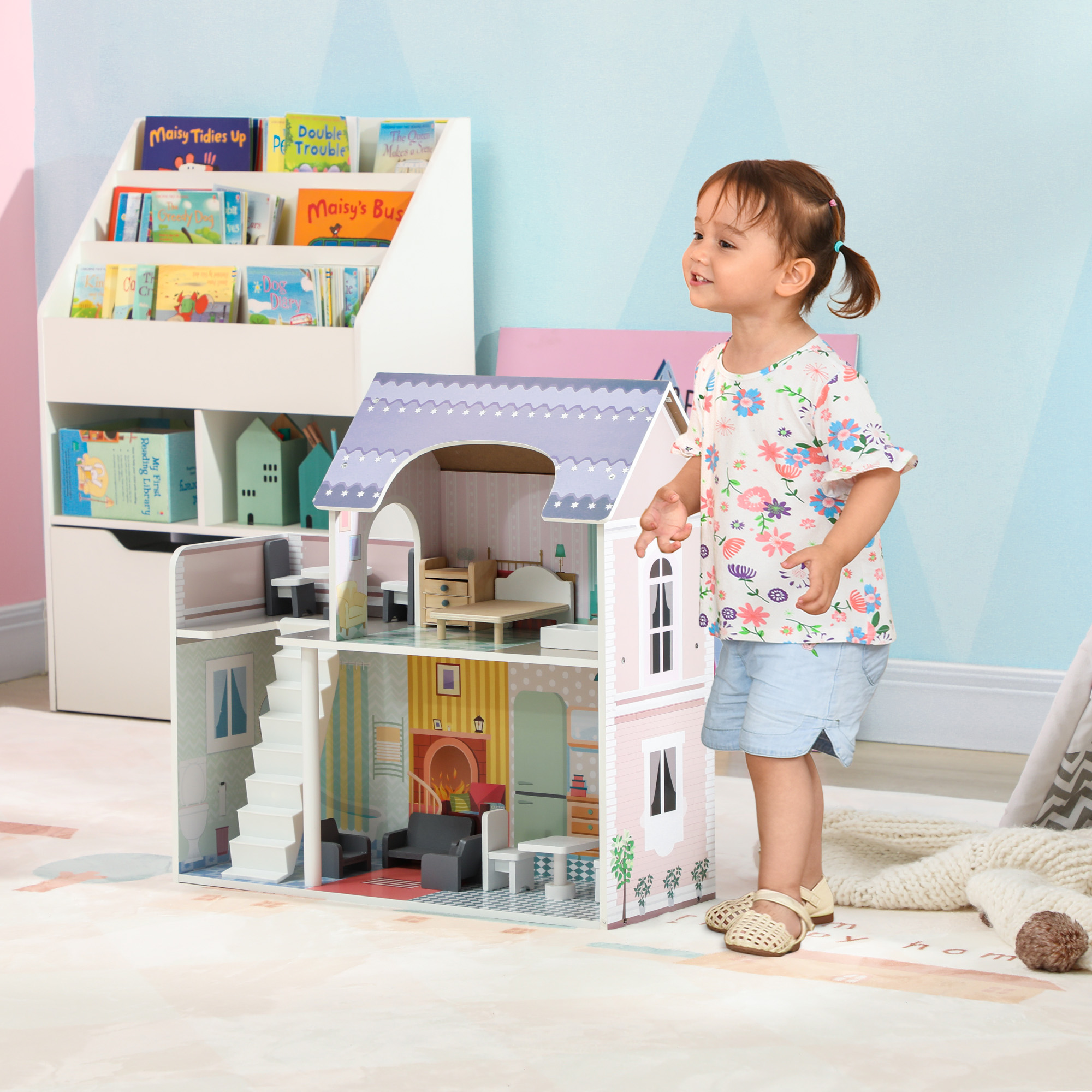 Una niña está junto a una casa de muñecas. Hay estanterías con libros detrás.