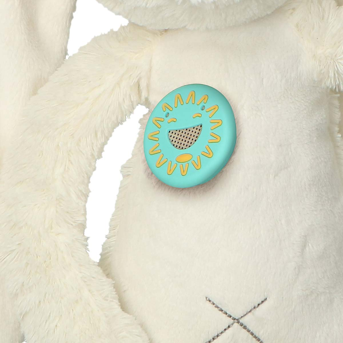 A fluffy white toy with a turquoise sun emblem on its chest.
