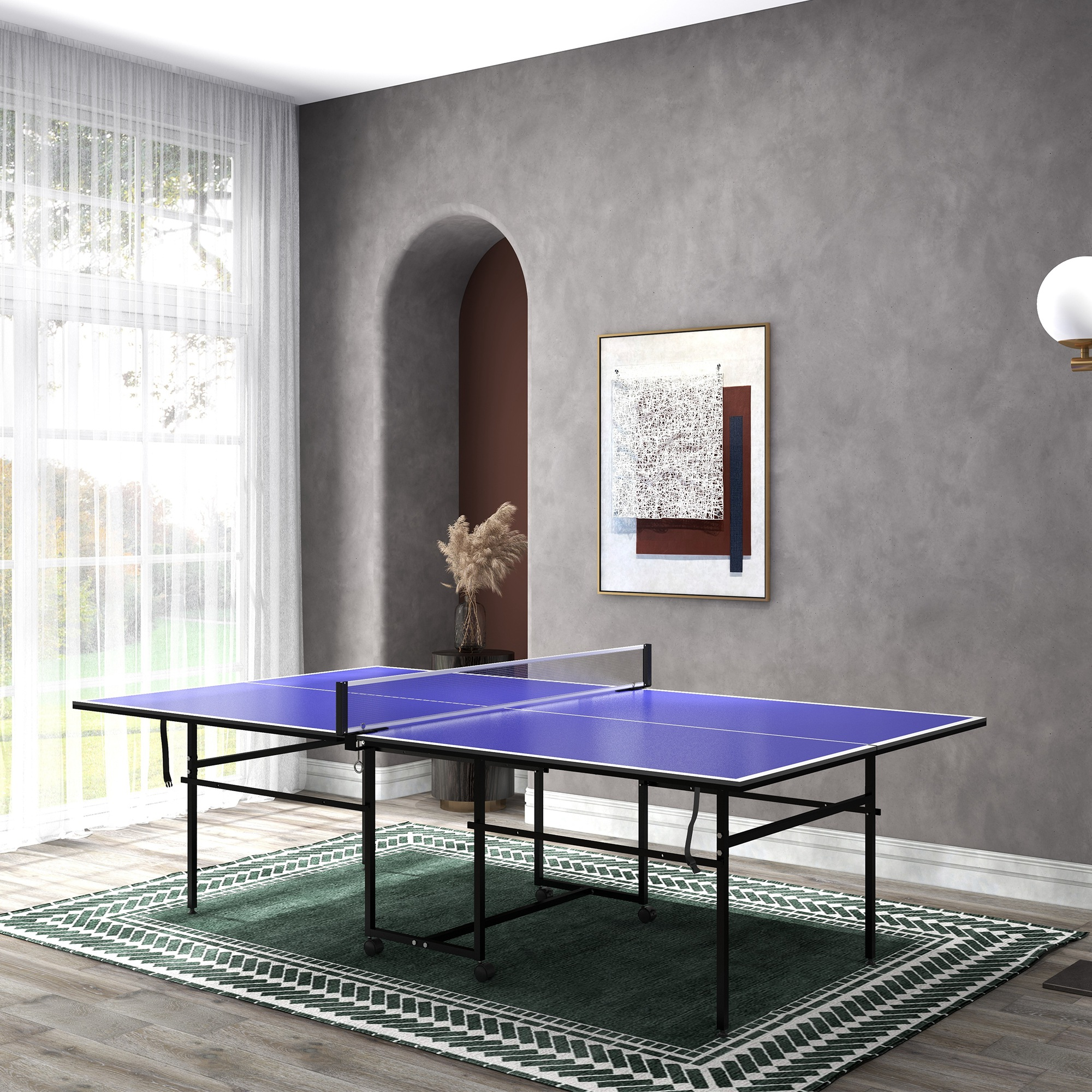 Una mesa de ping pong azul está sobre una alfombra verde frente a una ventana grande.