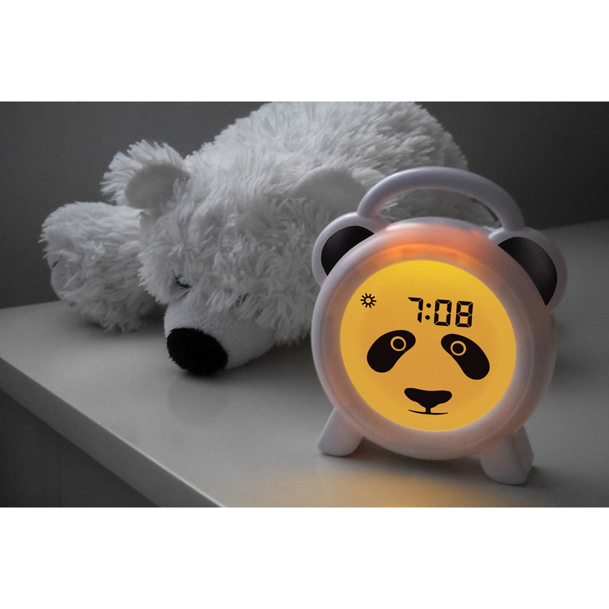 Ein weißer Teddybär liegt neben einem Panda-Nachtlicht mit der Uhrzeit 7:08.