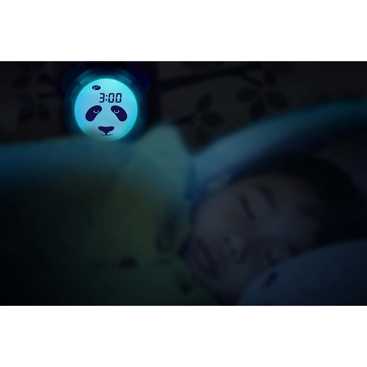 Ein Nachtlicht in Pandaform zeigt 3:00 Uhr. Ein Kind schläft im Vordergrund.